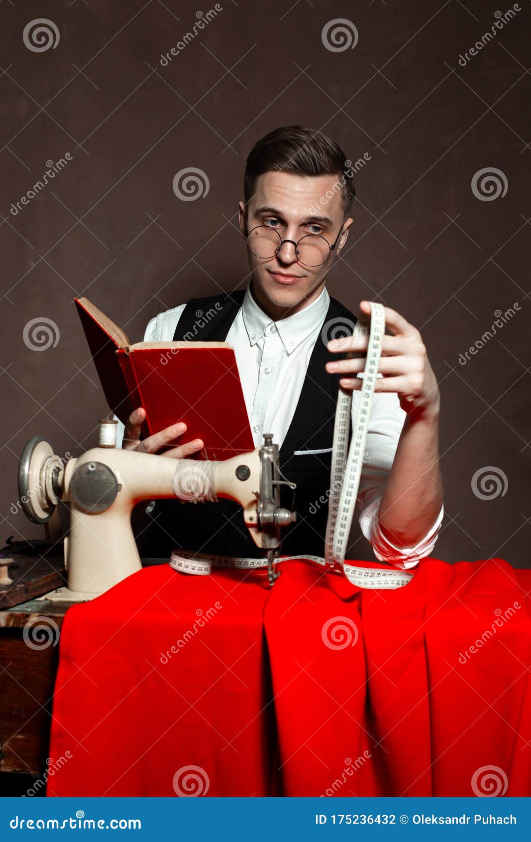 Tailor in Round Glasses Sits at a Table with a Sewing Machine Stock