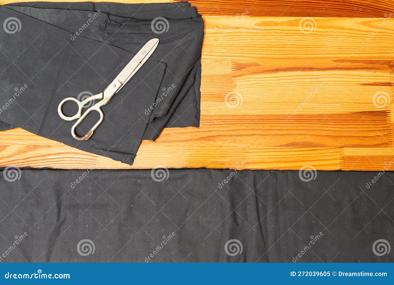 tailoring . old metal rusty scissors placed together with black fabrics on wooden surface
