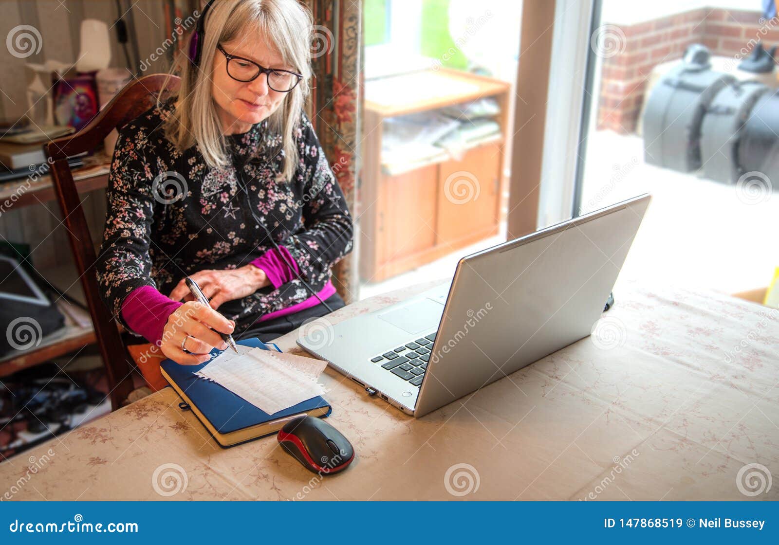 digital nomad woman watching webinar on her laptop,wearing headphones
