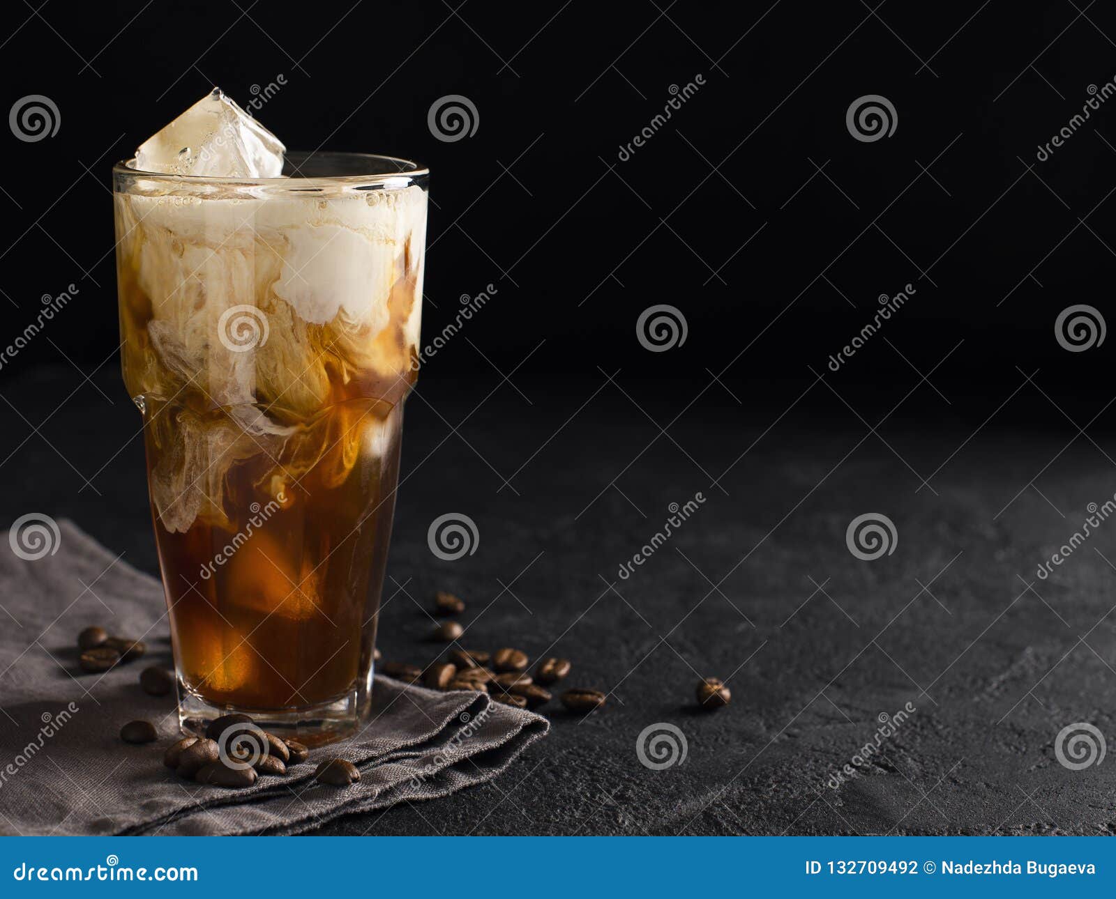 tall glass cold brew coffee with ice and milk on black or dark b