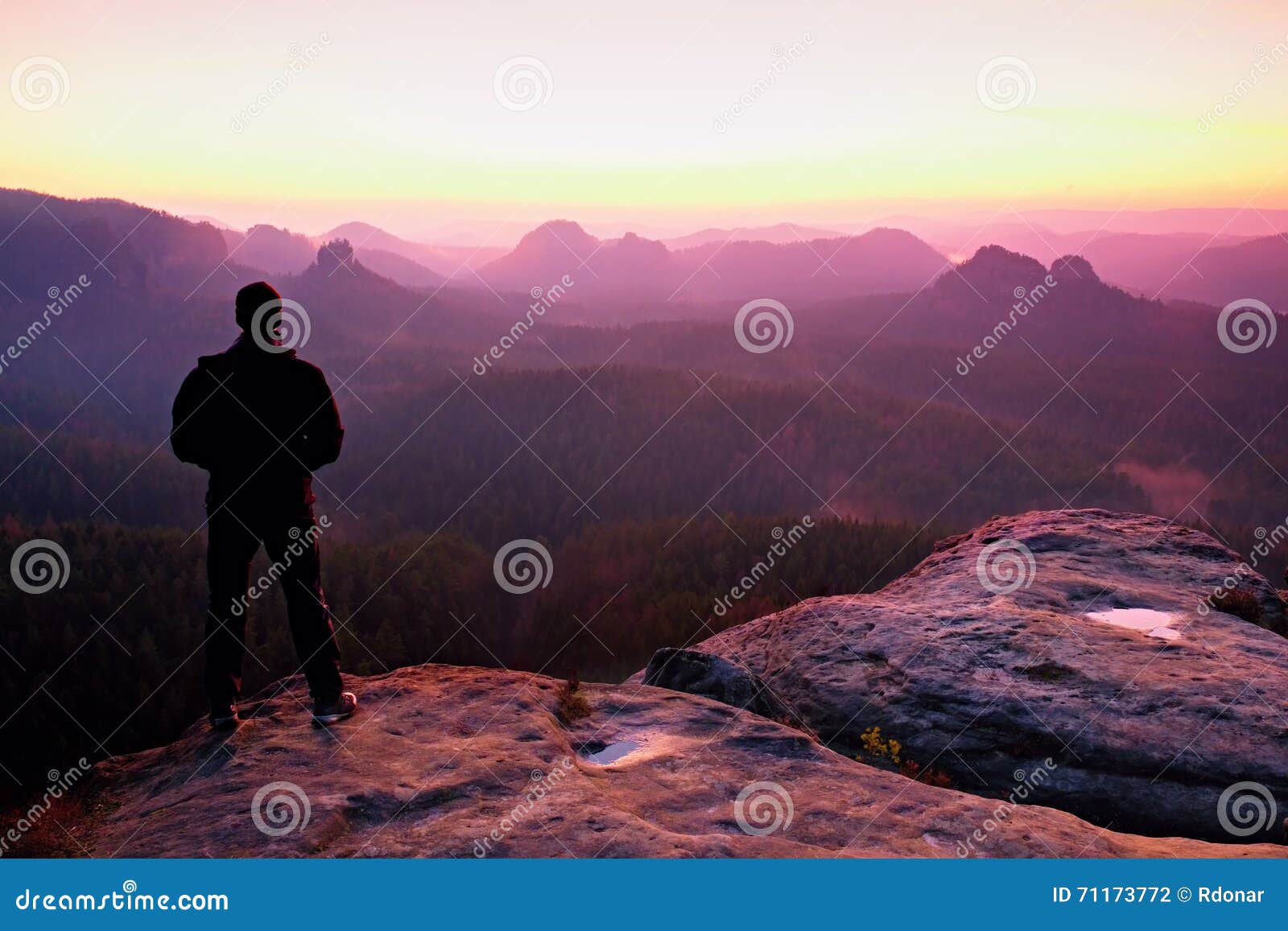 tall man in black on cliff and watch to mountain sunrise.silhouette in selfconfident pose