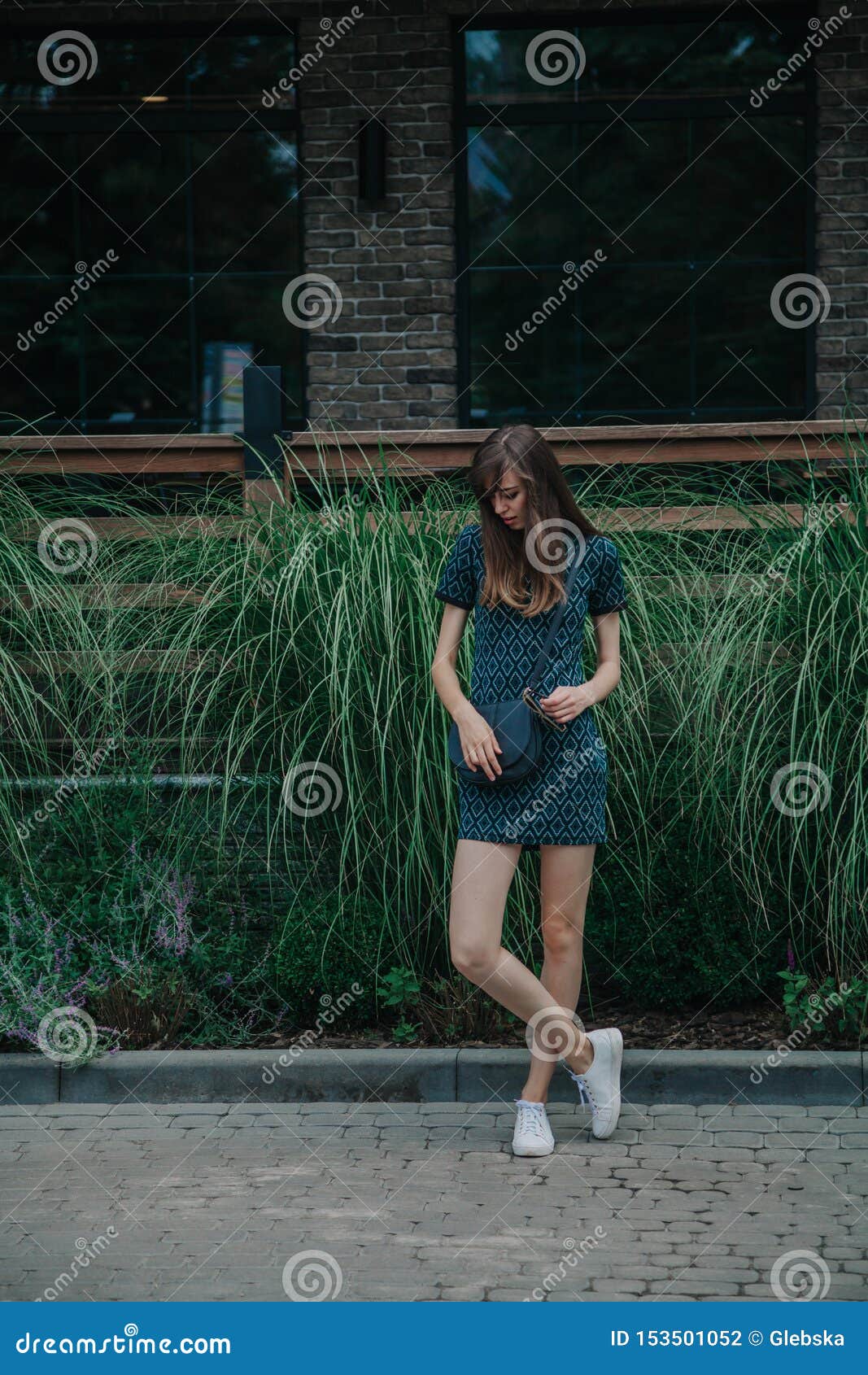 Slim Tall Girl In Green Dress Walks Along Avenue Stock Photo
