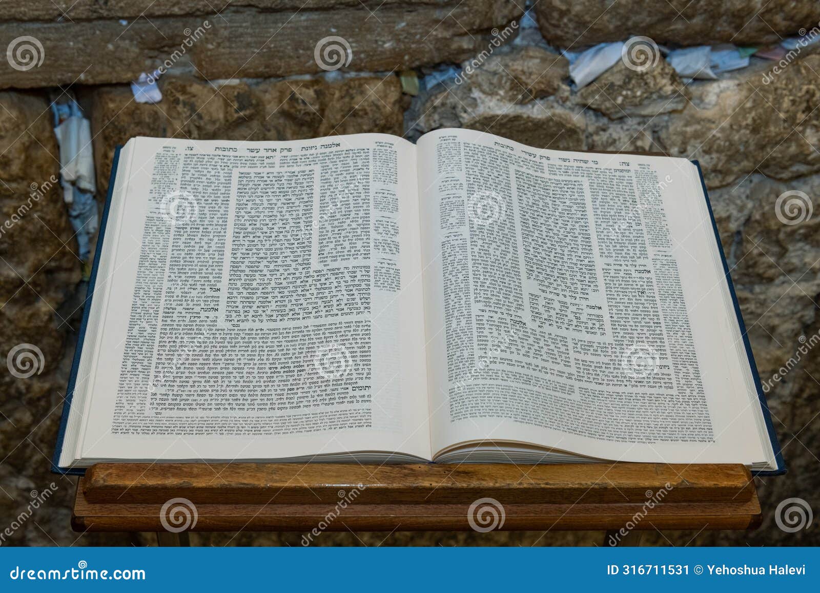 an open talmud on a stand in front of the western wall in jerusalem.
