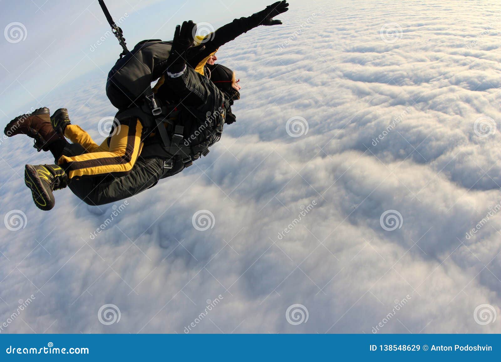tandem skydiving. skydivers are flying above white clouds.