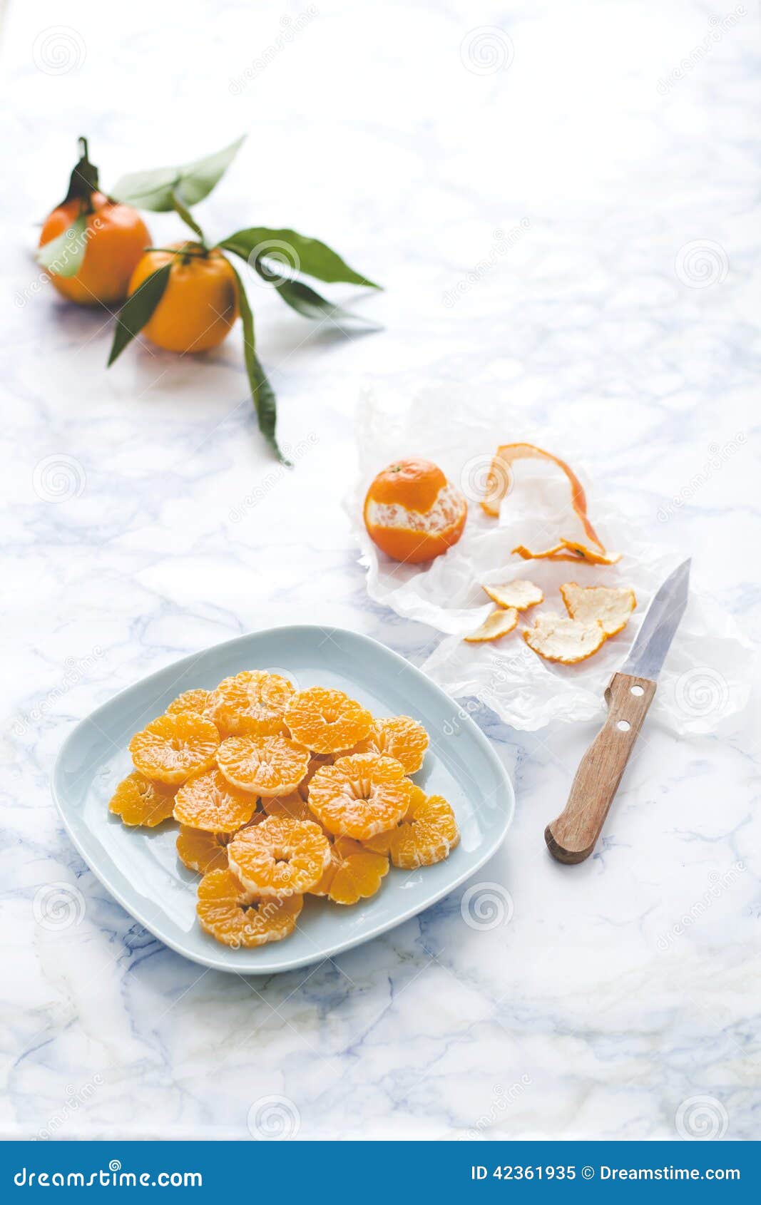 Tangerines salad. Sliced and peeled tangerines on a little plate with wooden knife and other tangerines
