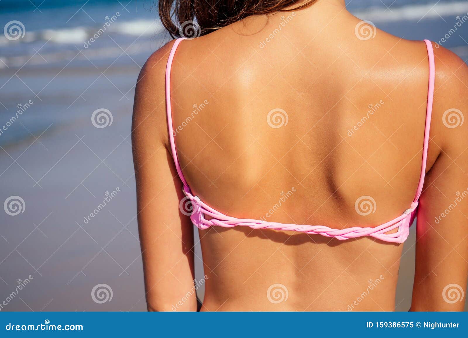 Foto de beautiful tanned female fitness big boobs model holding spf bottle  applying on the chest in a fashion stylish swimsuit on sea ocean beach blue  sky and palm trees background.summer vacation