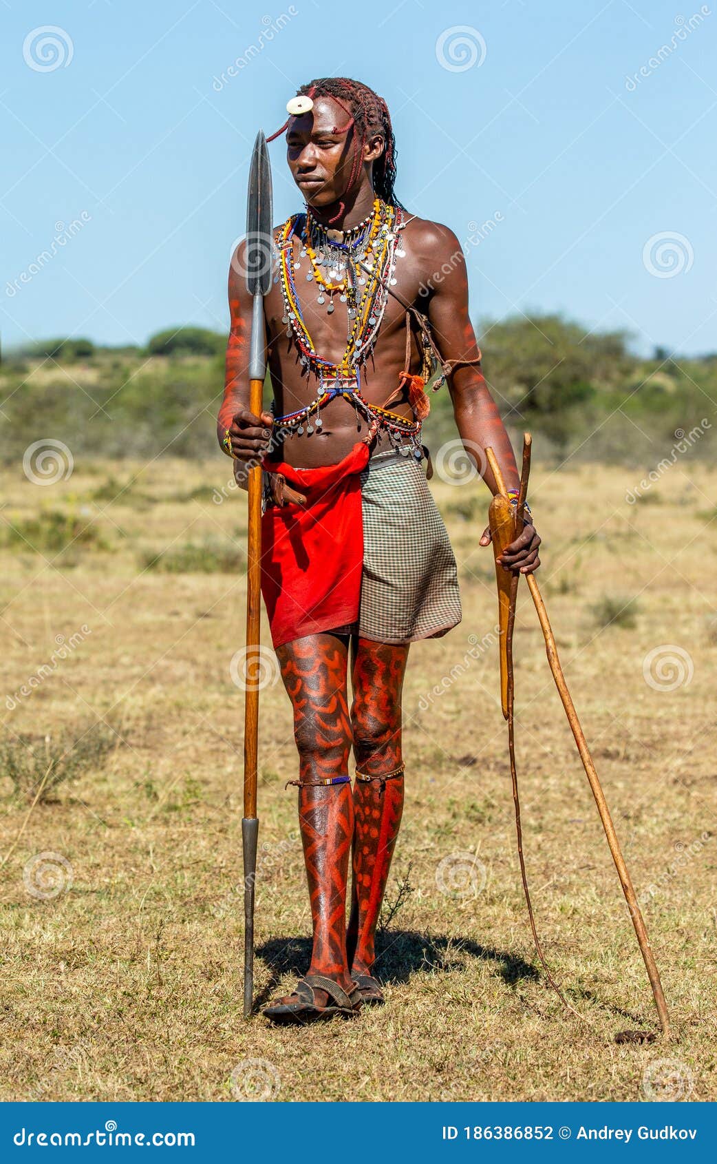Young Masai Warrior is Standing in Traditional Clothing with a Spear in
