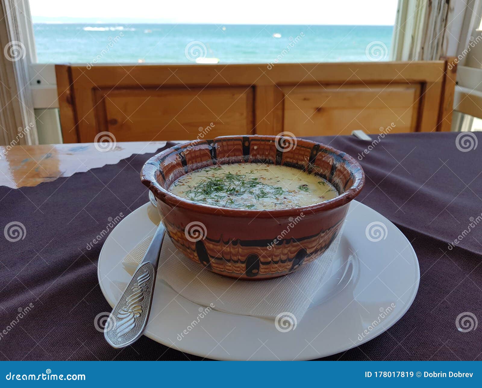 tarator - bulgarian cuisine. summer cold soup with yogurt, herbs, walnuts and cucumber for healthy diet. meal infront of sea