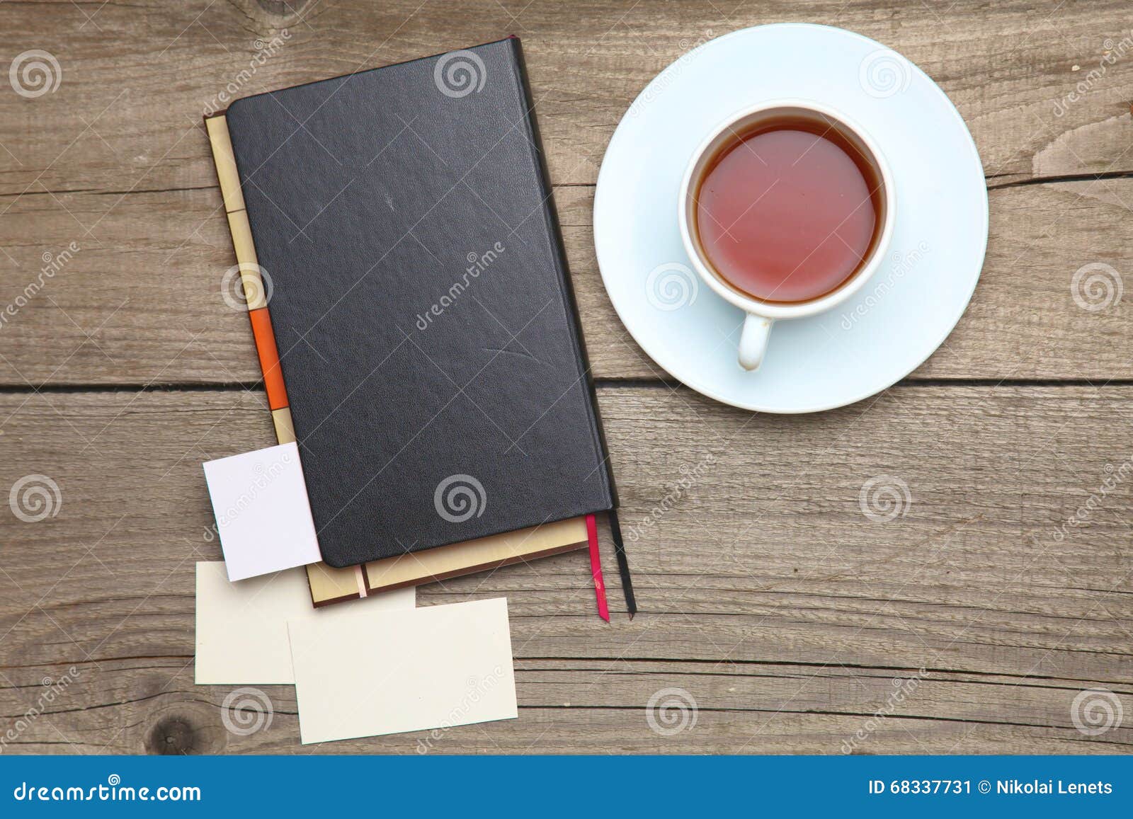 Tarjetas de visita en blanco con la pluma, el cuaderno y la taza de té en la tabla de madera de la oficina