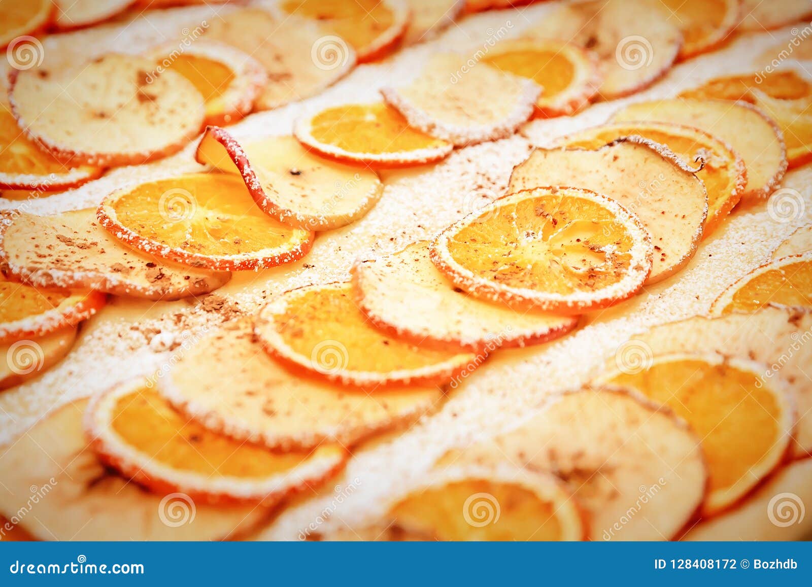 une bougie blanche décorée de tranches d'orange et de pomme et