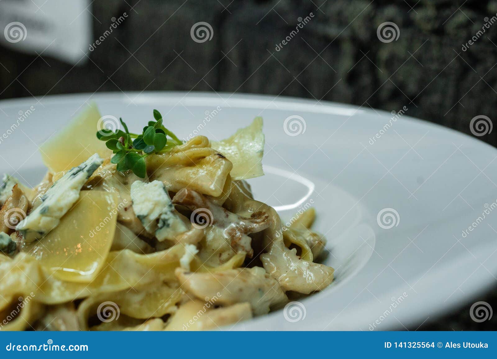 tasty hot noodle with cream sauce with fried mushrooms and roquefort cheese in a bar on a brick wall background.