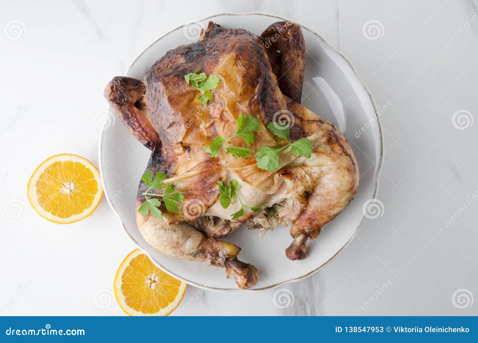tasty hot roasted chicken with oranges on big plate on wite marble table,top view