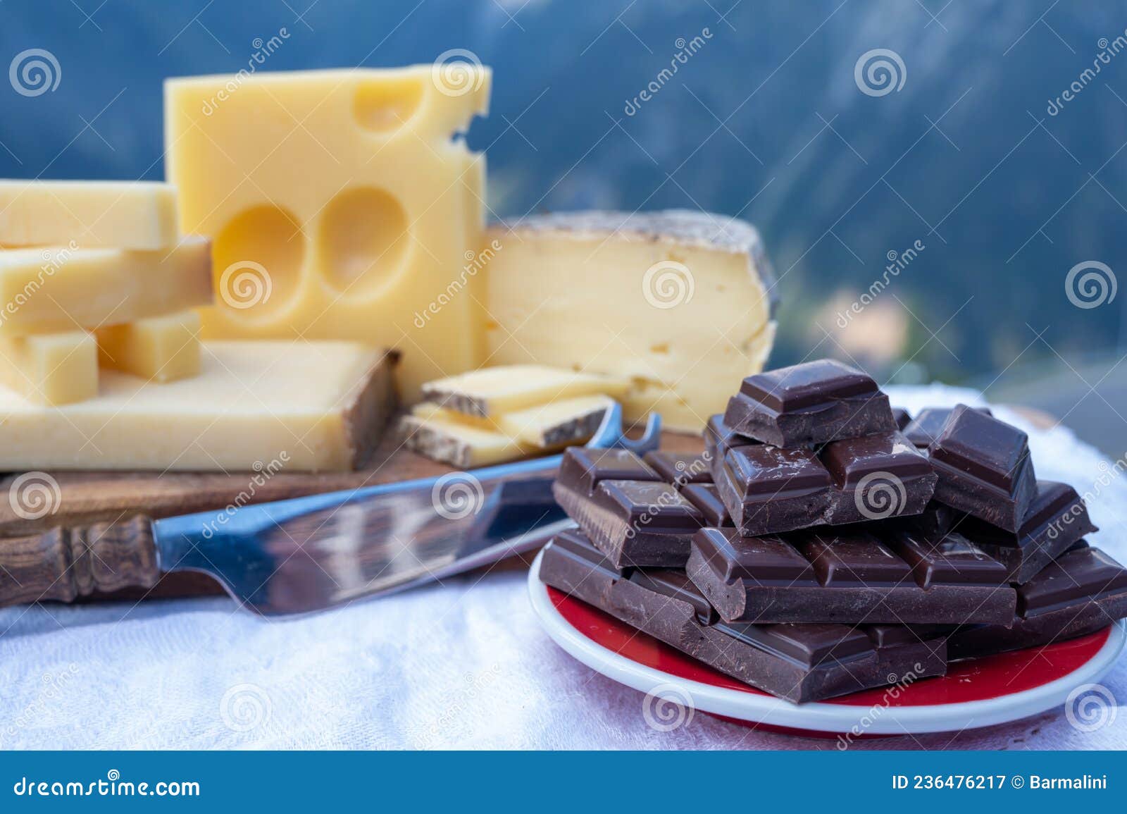 tasty swiss cheeses and dark pure chocolate, emmental, gruyere, appenzeller served outdoor with alpine mountains peaks on