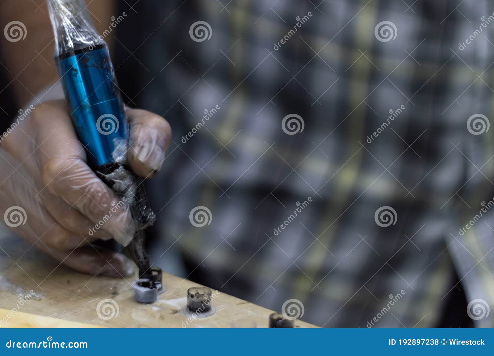 Tattoo Artist Holding a Tattoo Machine and Dip into Inks for Tattooing