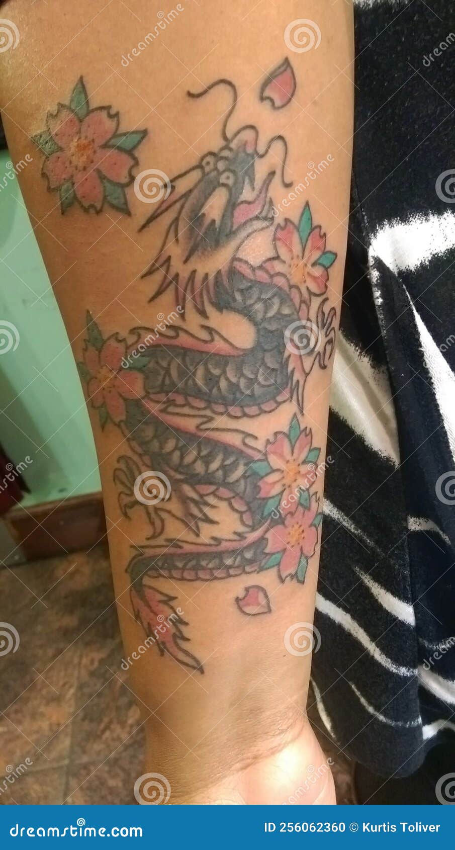 Forearm sleeve tattoo of a dragon fighti...