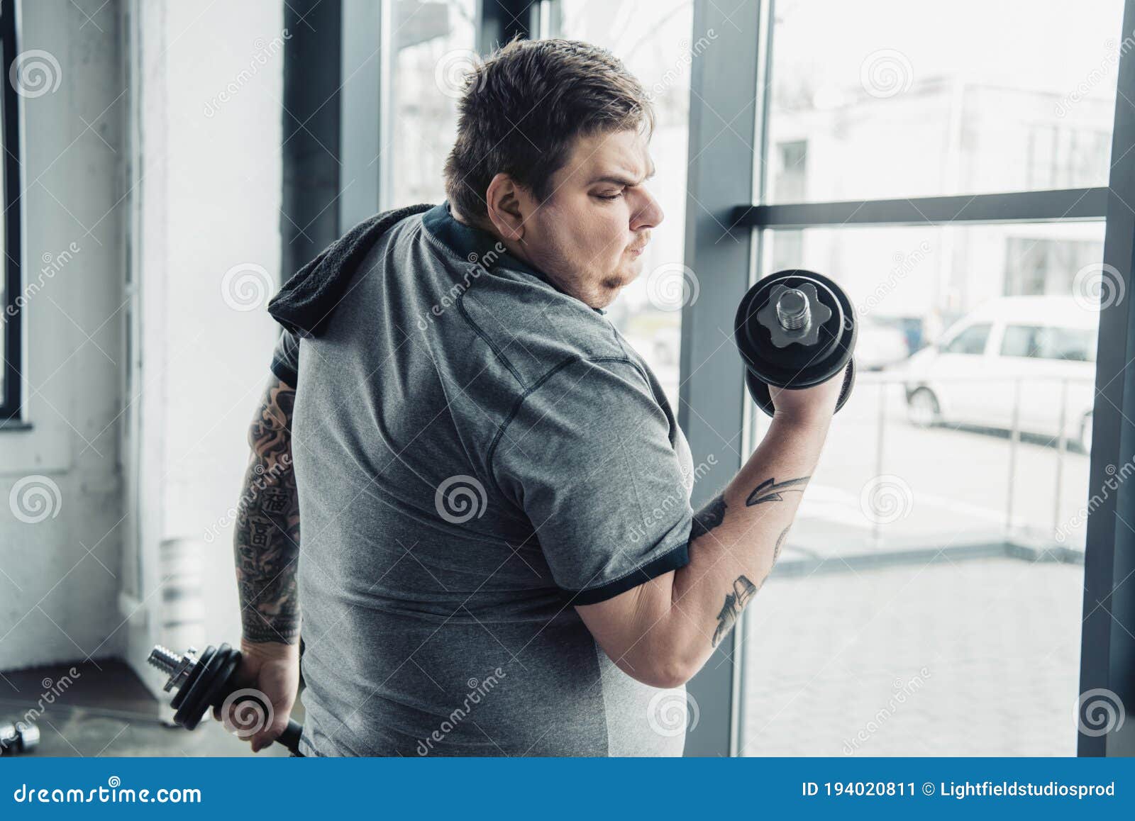 Tatuerad Man Med Handduk Som Tränar Med Dumbom Vid Sportcentrum  Fotografering för Bildbyråer - Bild av vikt, weightliftingen: 194020811
