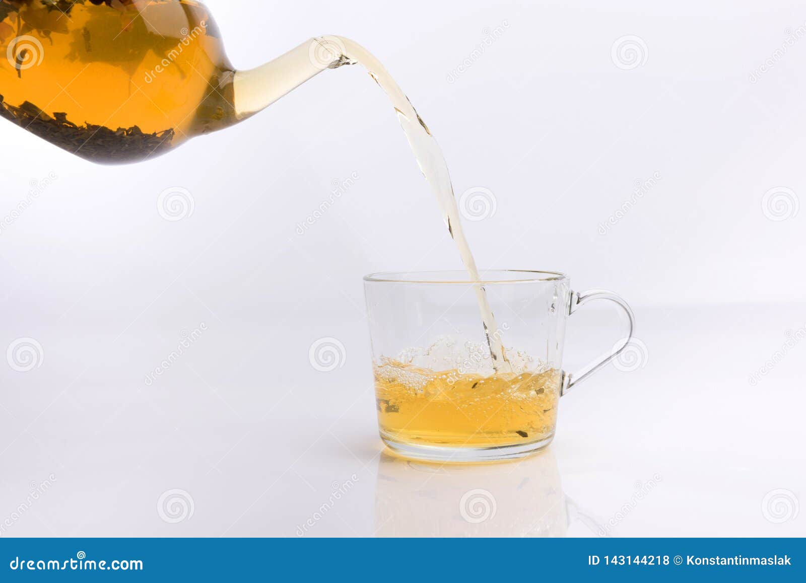 Glass Teapot Pouring Green Tea into Cup on White Background Stock Photo