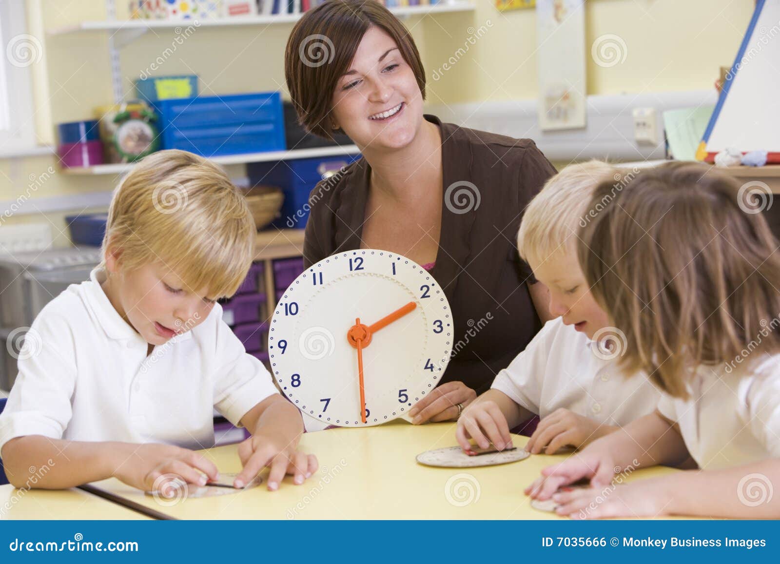 teacher helping schoolchildren learn to tell time
