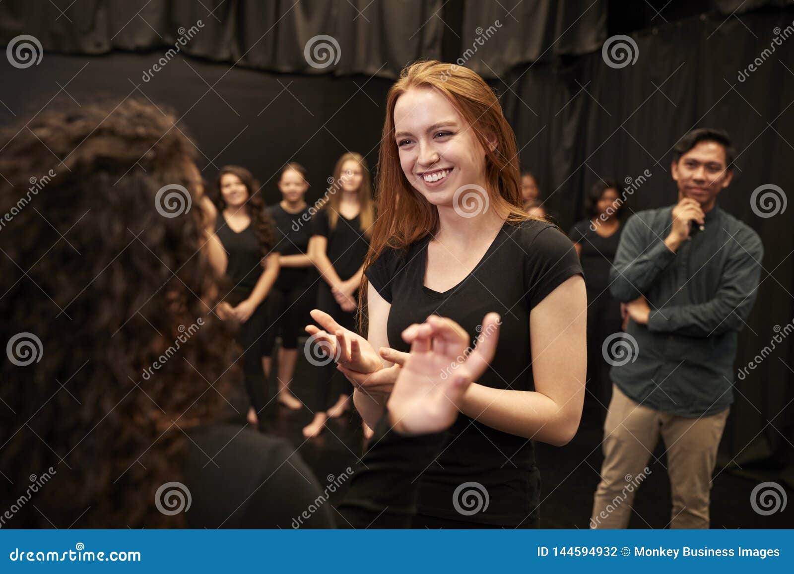 teacher with male and female drama students at performing arts school in studio improvisation class