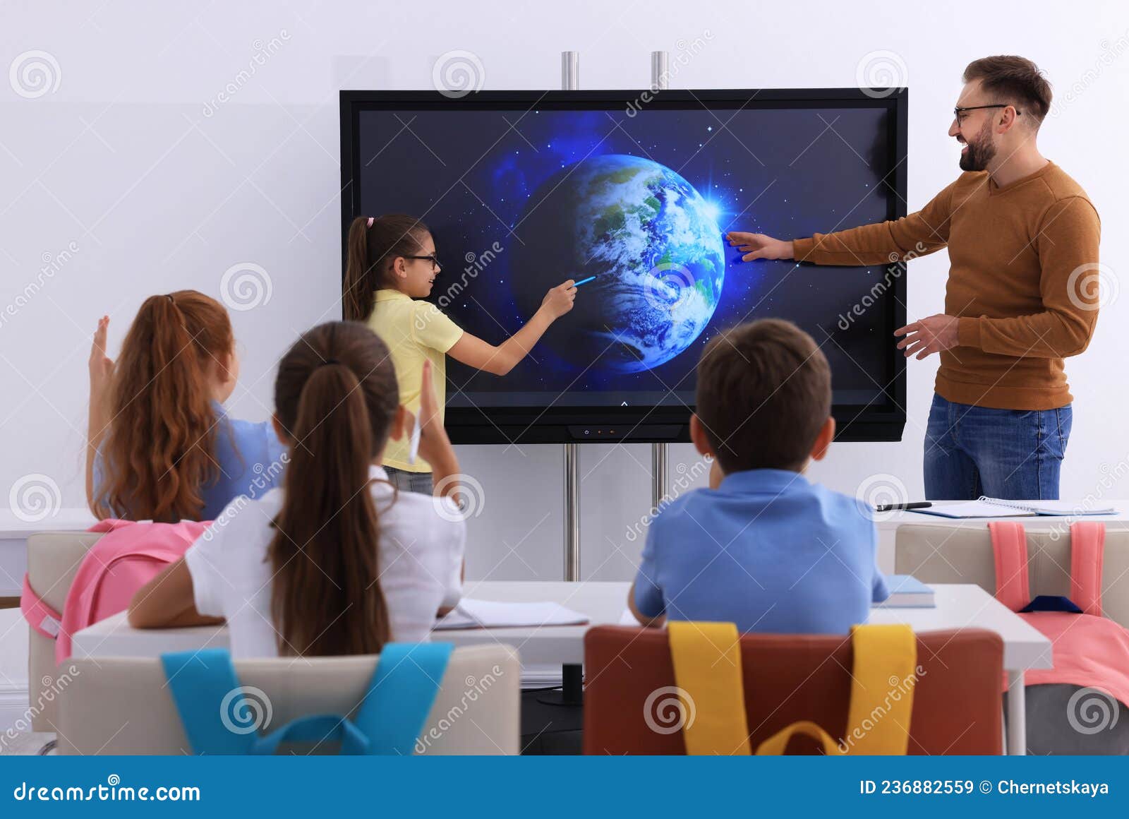 teacher and pupil using interactive board in classroom during lesson