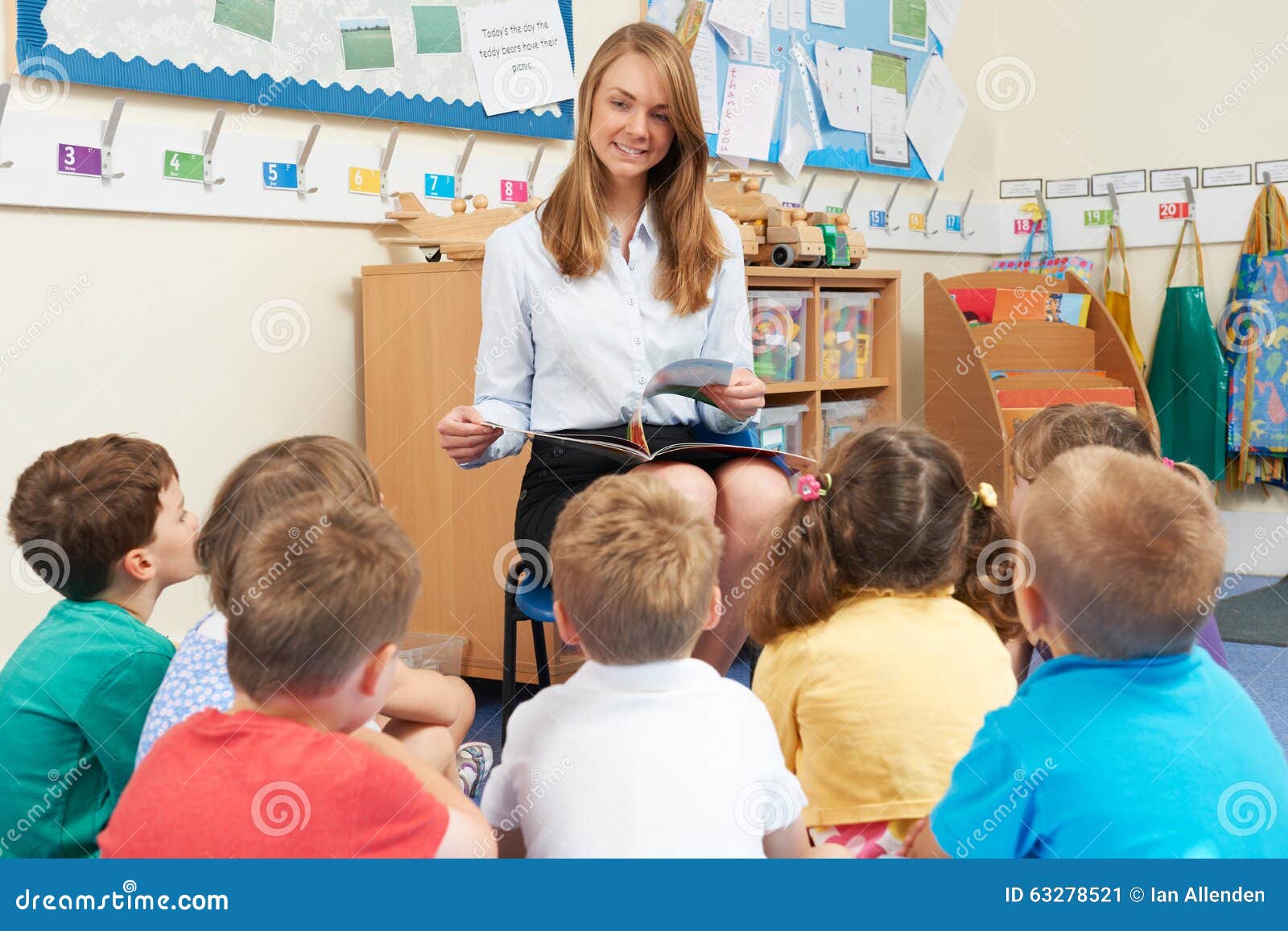 teacher reading book to ary school class