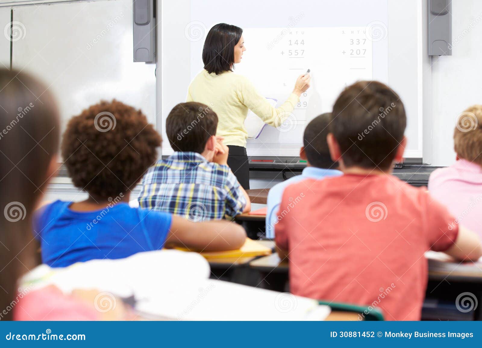 teacher standing in class using interactive whiteboard