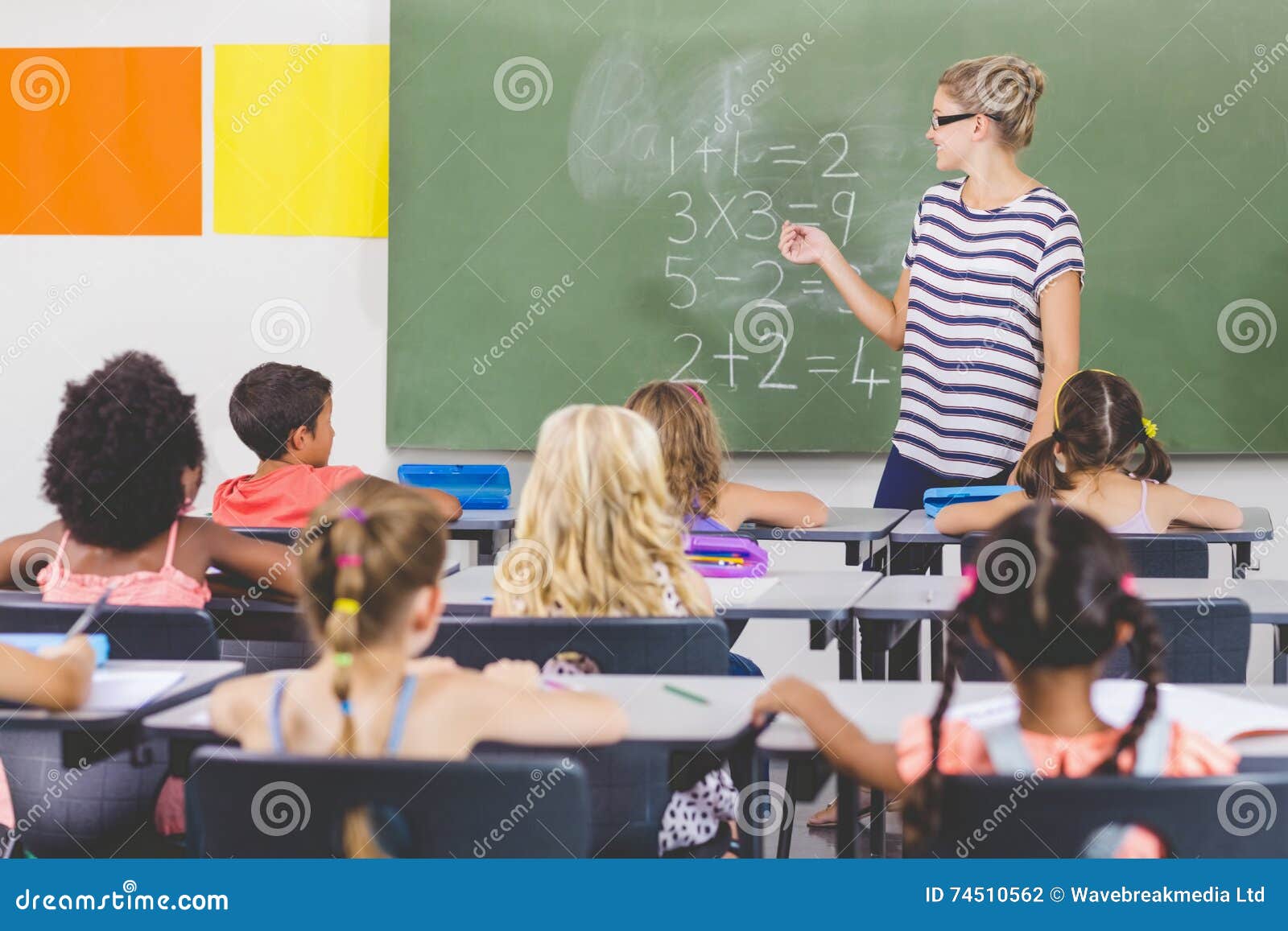 teacher teaching mathematics to school kids in classroom