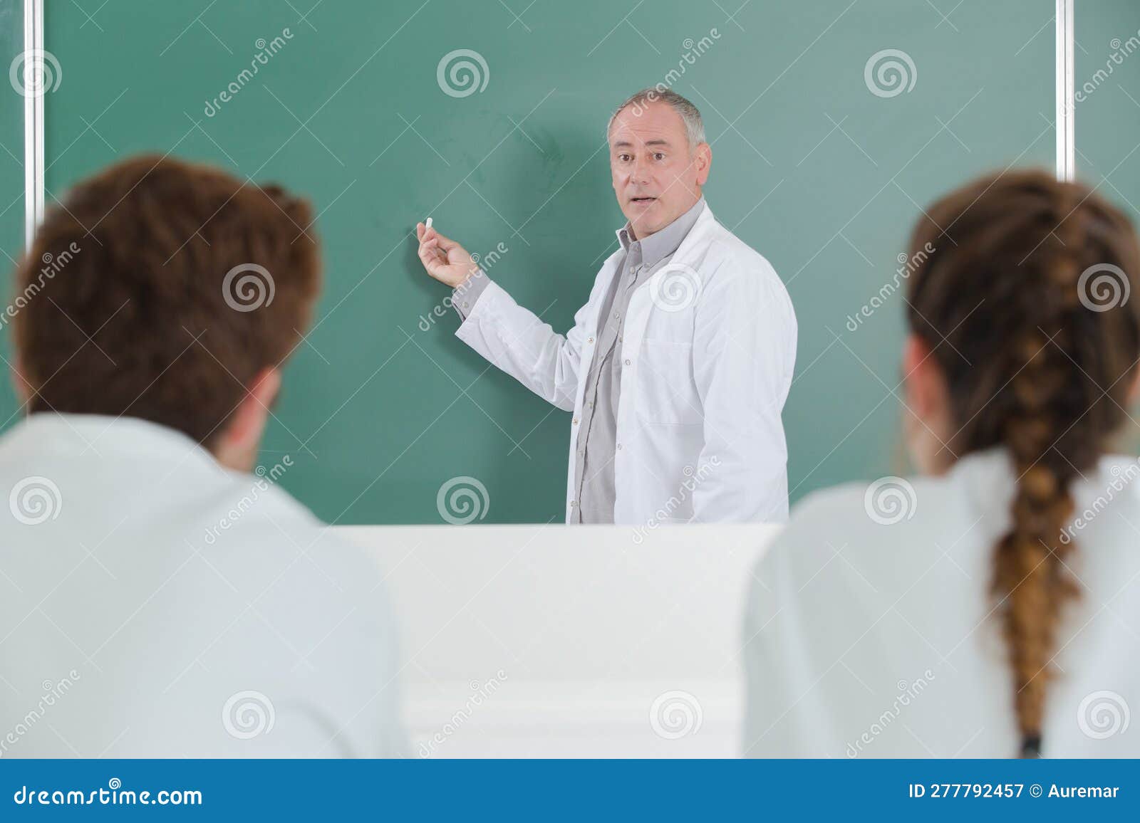 Teacher Writing on Blank Green Chalkboard in Classroom Stock Image