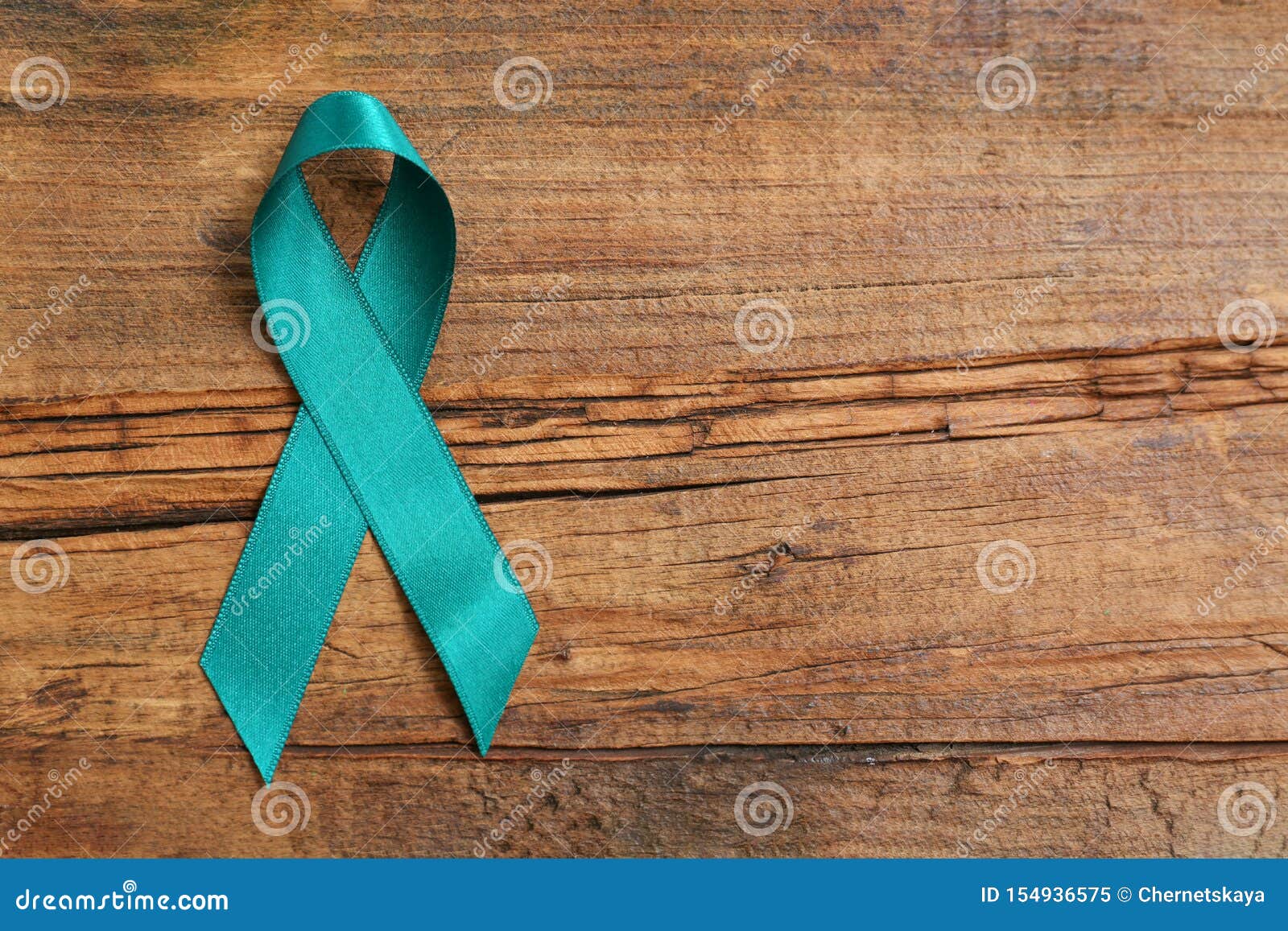 teal awareness ribbon on wooden background, top view with space for text.  of social and medical