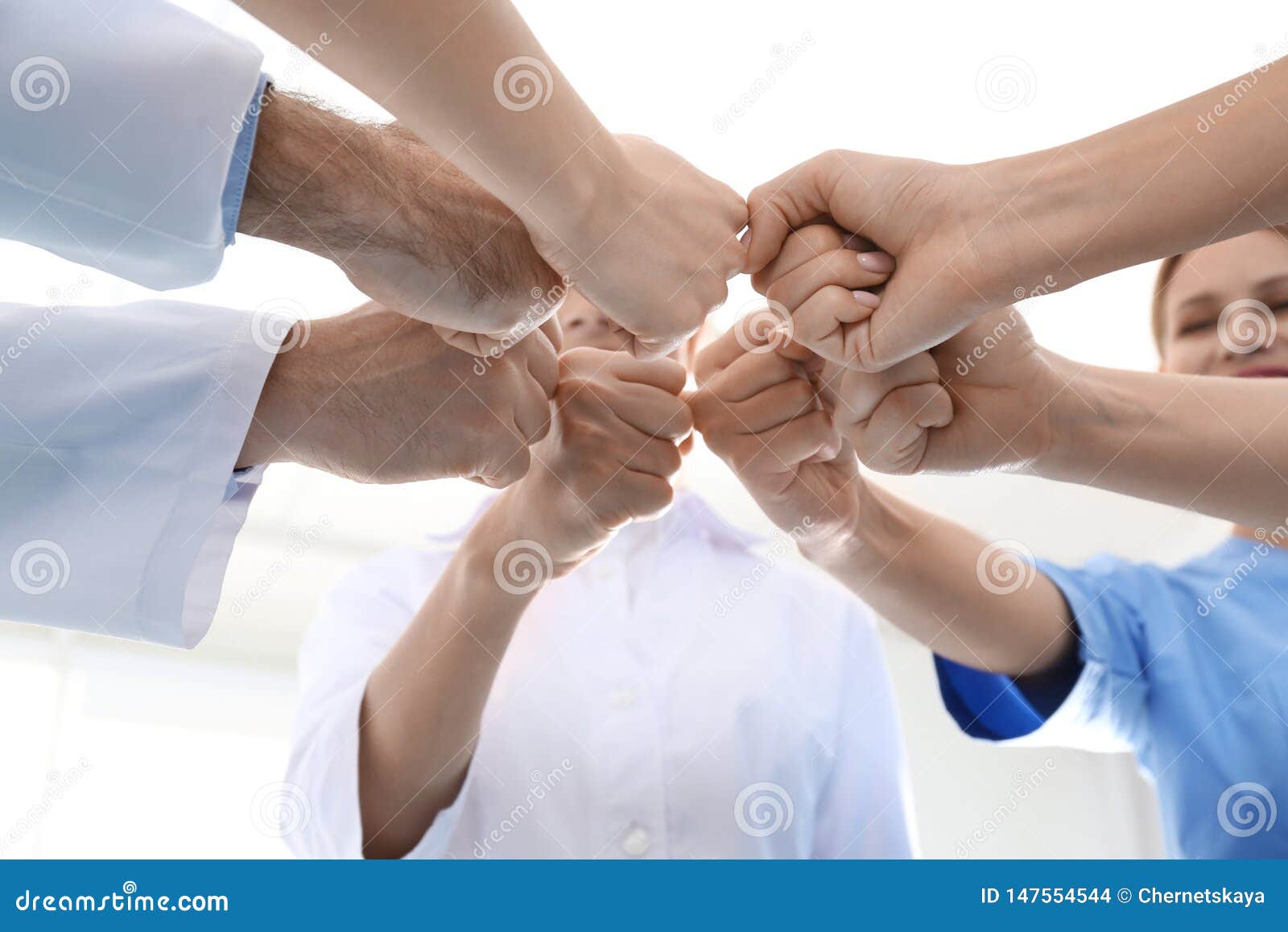 team of medical doctors putting hands together on light background. unity concept