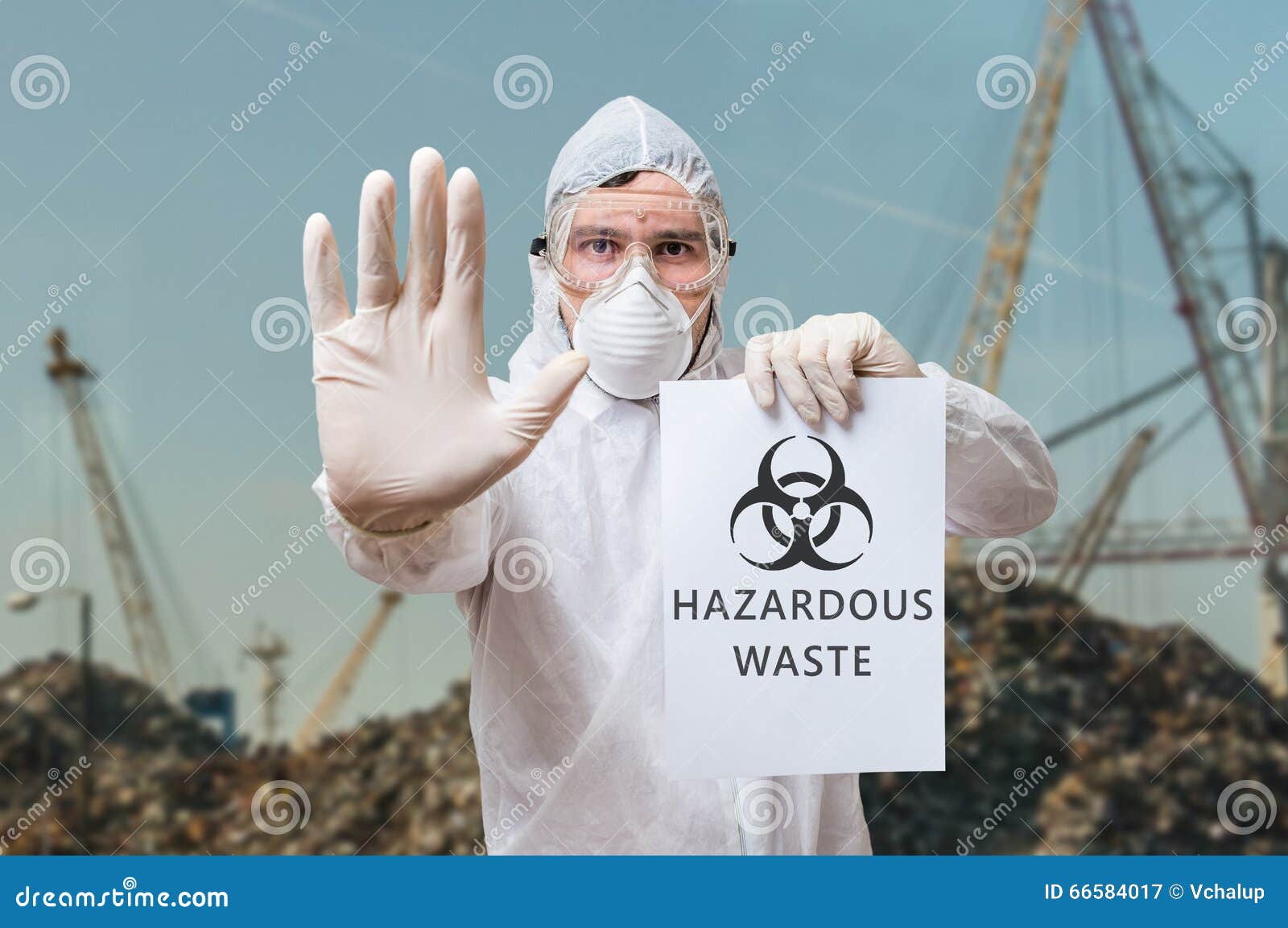 technician in coverall warns in landfill about hazardous waste