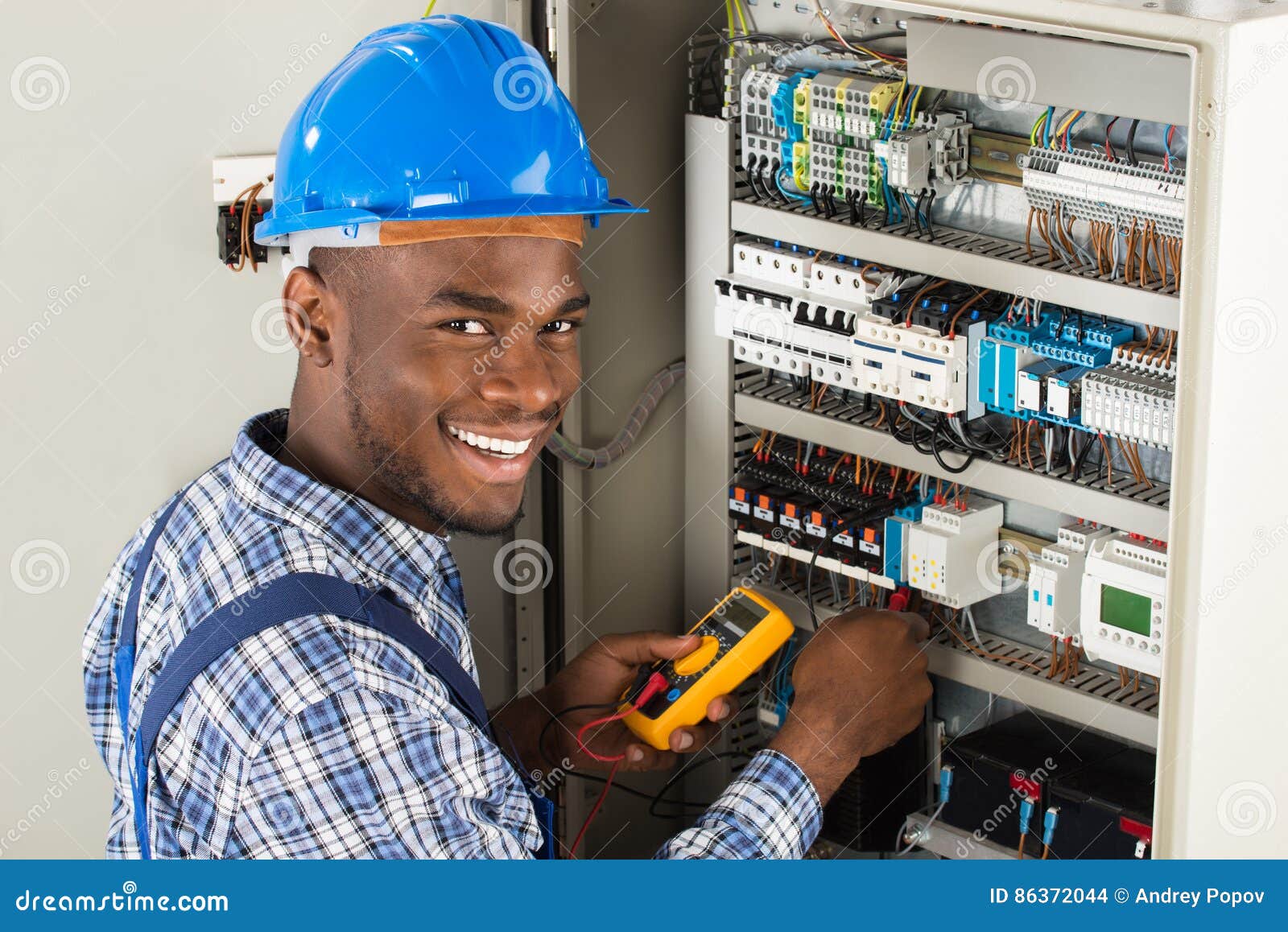 technician examining fusebox with multimeter probe