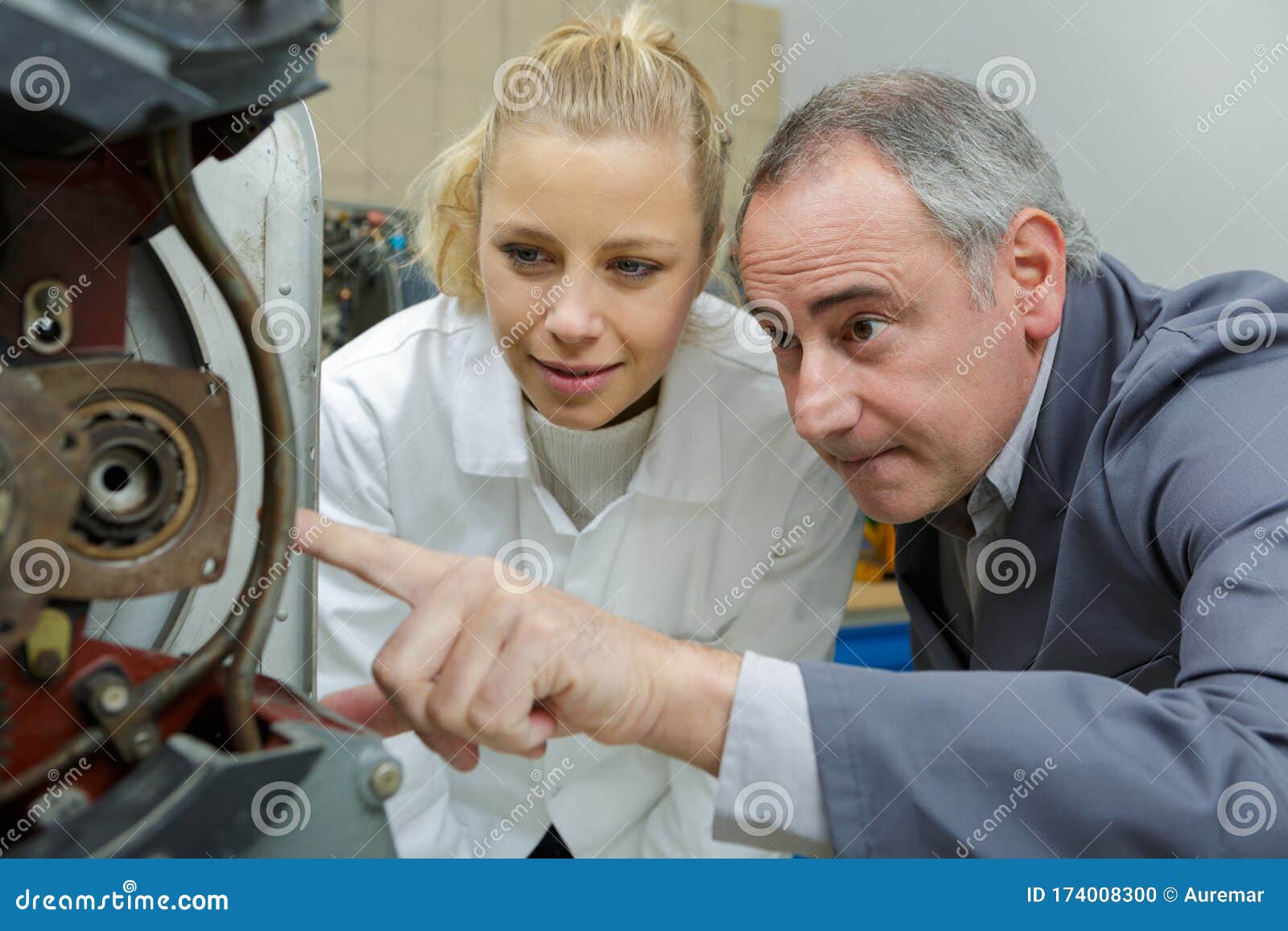 Technician Explaining Working Aircraft Part To Female Apprentice Stock