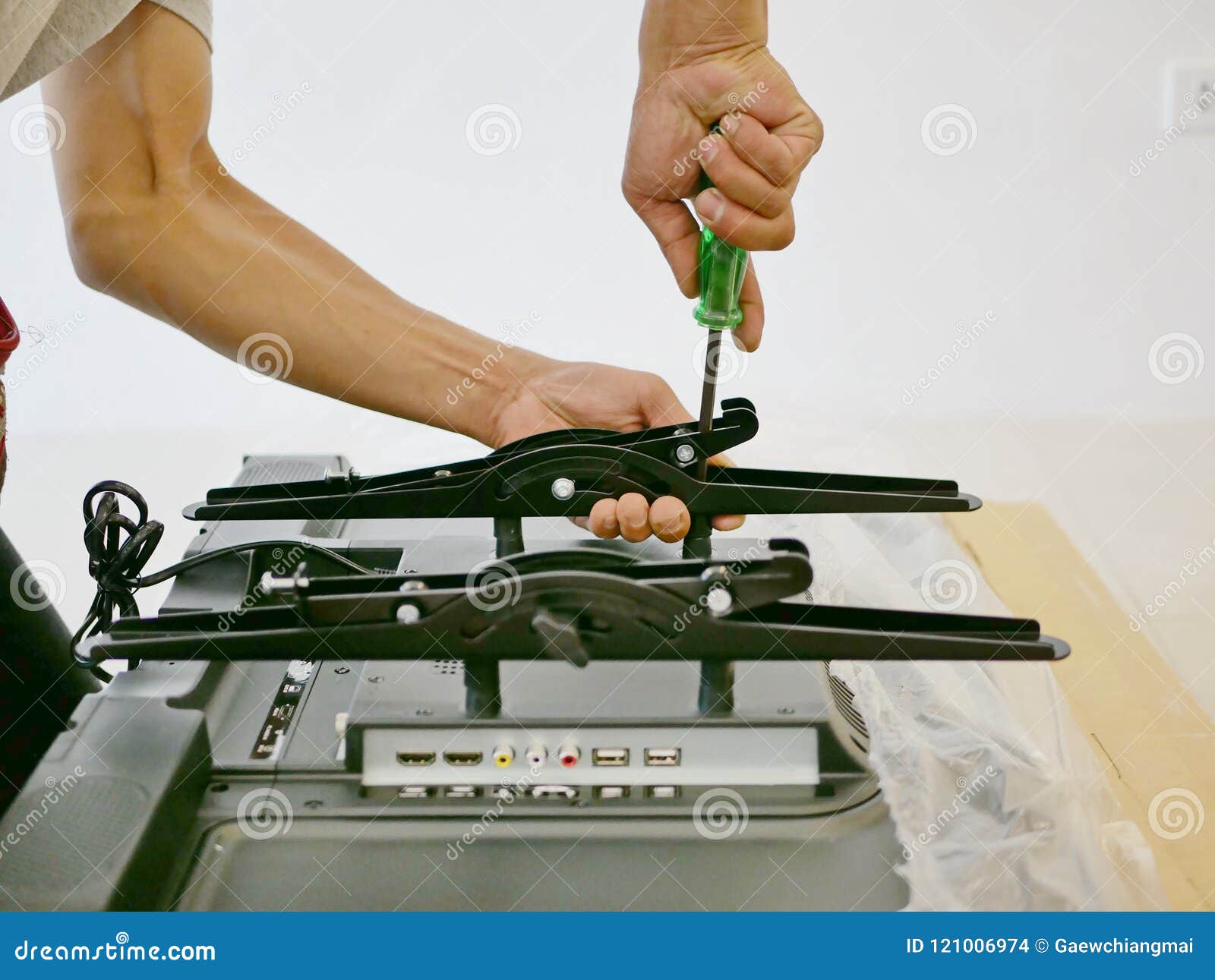 A Technician is Installing a Wall Mount on the Back of a Television