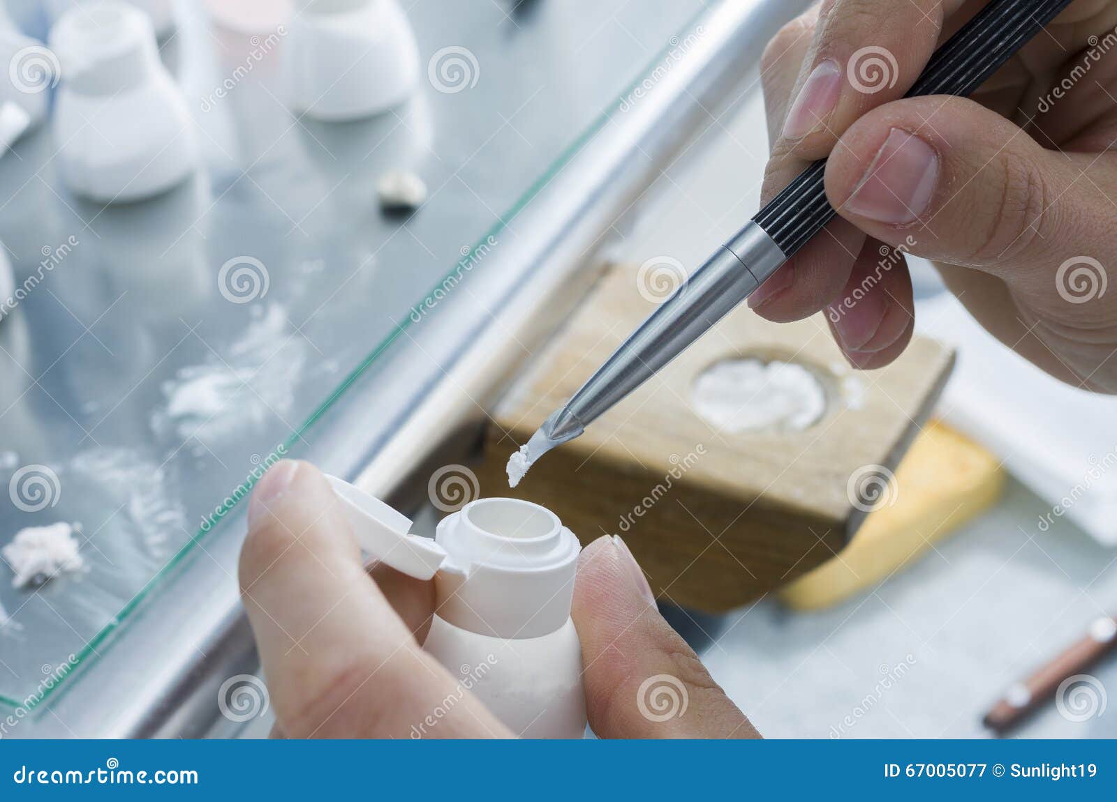 technician putting the ceramic material in powder in the glass.