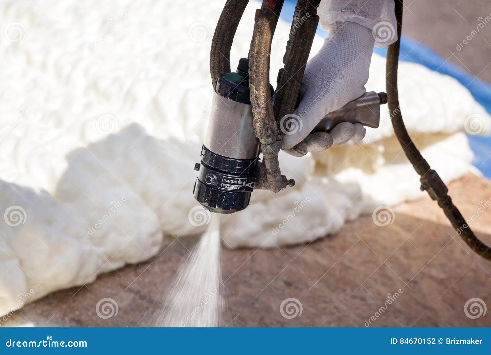 technician spraying foam insulation using plural component spray gun.