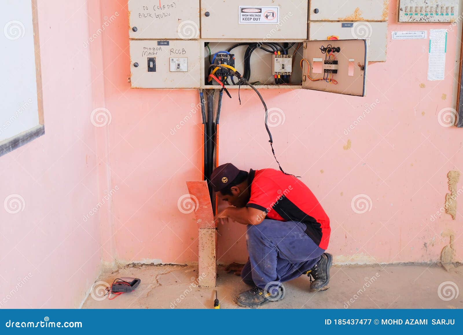 Technician Wiring Cable in Front of Electrical Panel for Control and