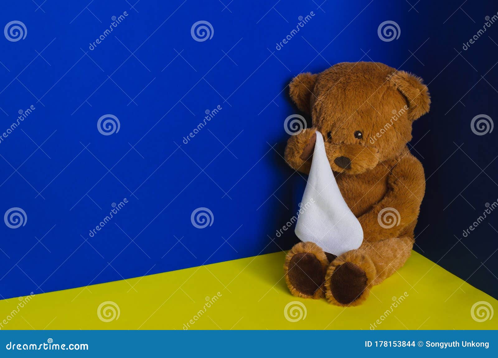 Teddybärpuppe, die an der Ecke sitzt und mit Taschentuch schreit..