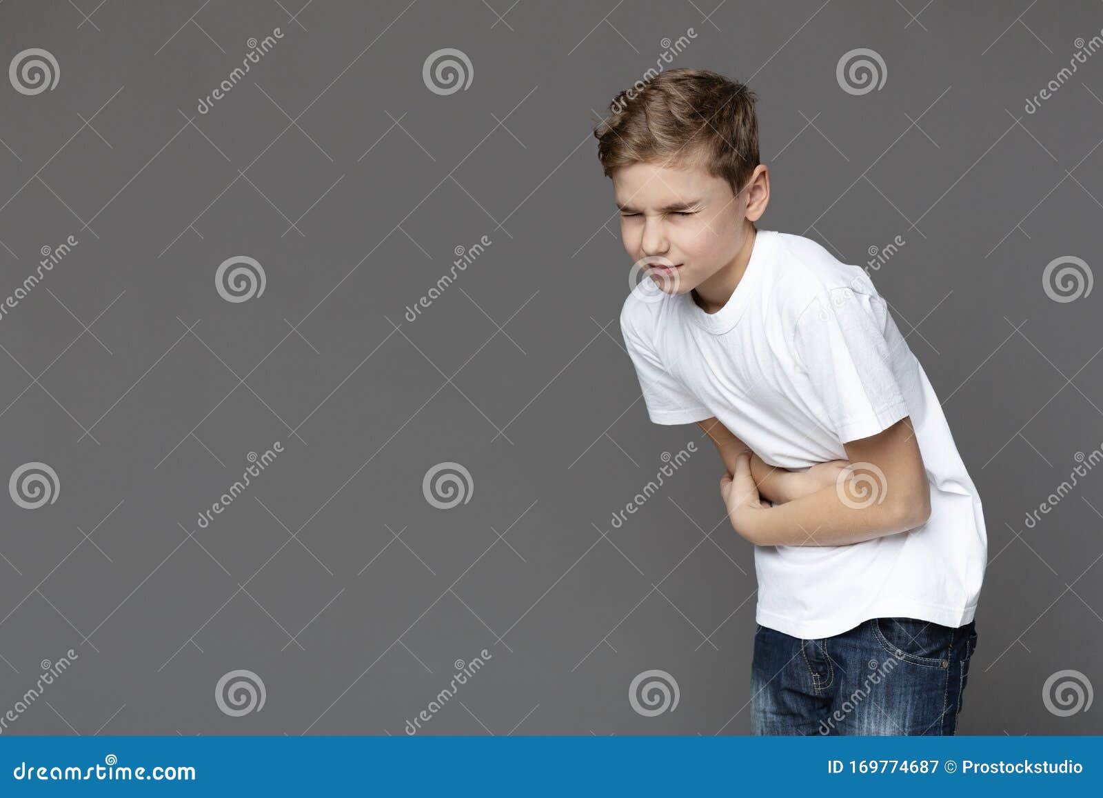 teen boy suffering from stomachache, grey background
