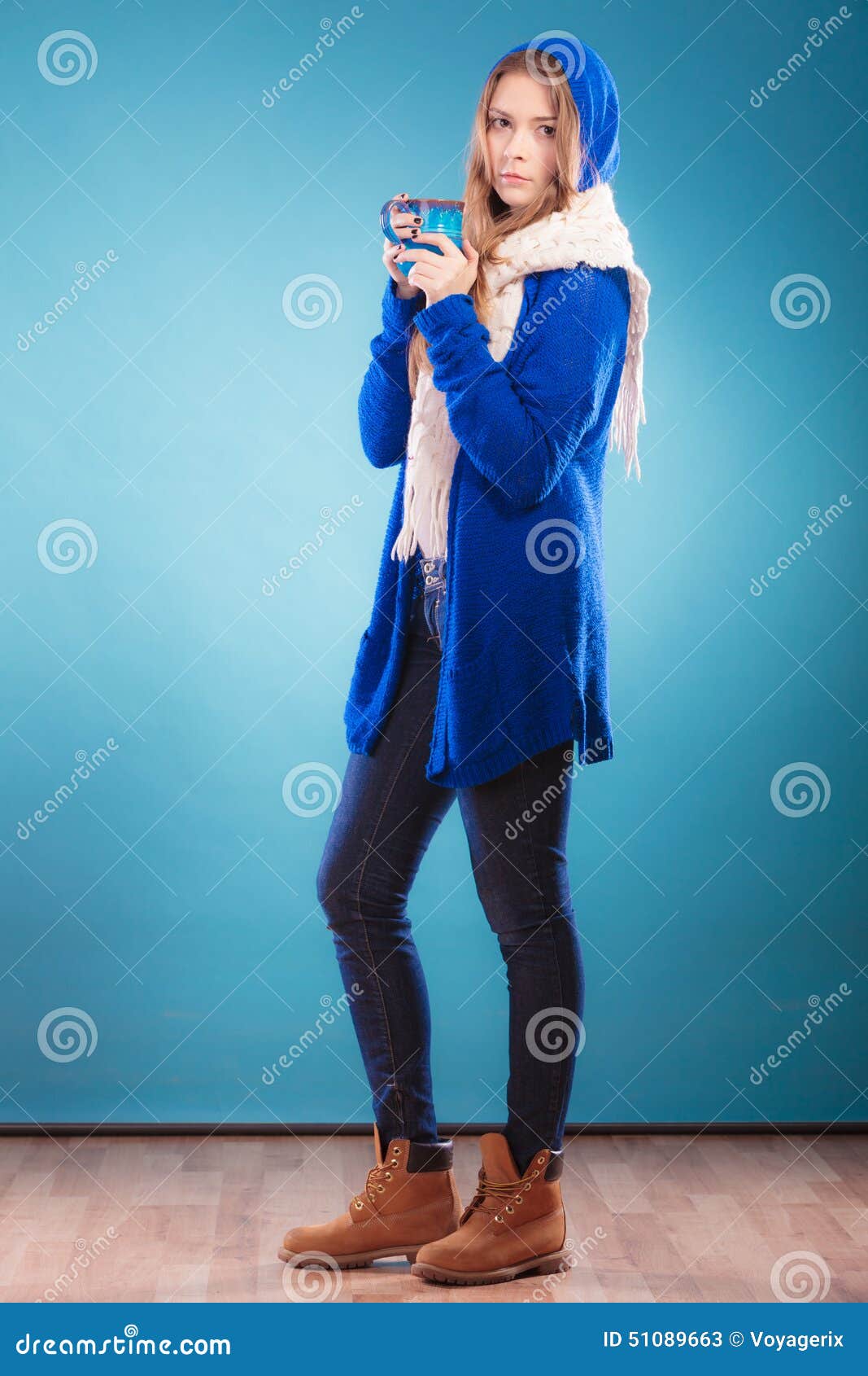 Teen girl holding blue mug with hot drink. Hot beverage. Full length teen girl holding blue mug with drink tea or coffee. Woman warming herself studio shot