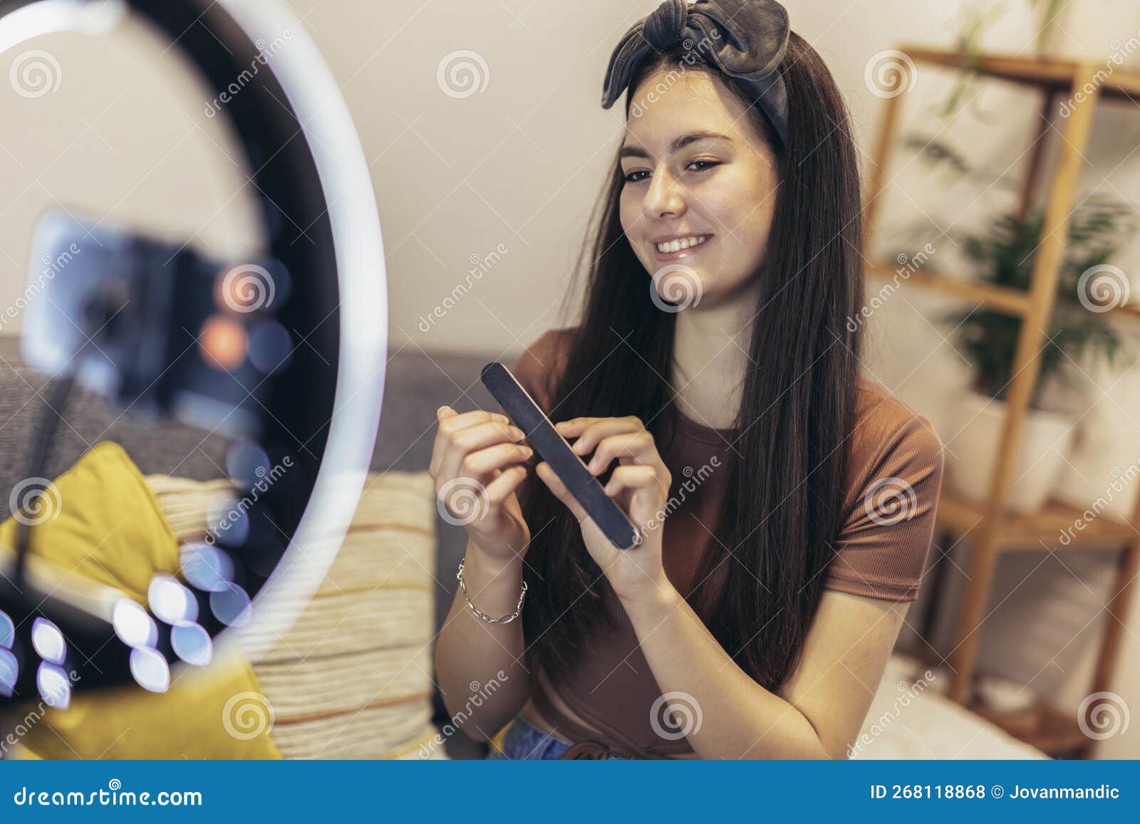 teen girl vlogger live broadcasting make up tutorial to her followers via smart phone