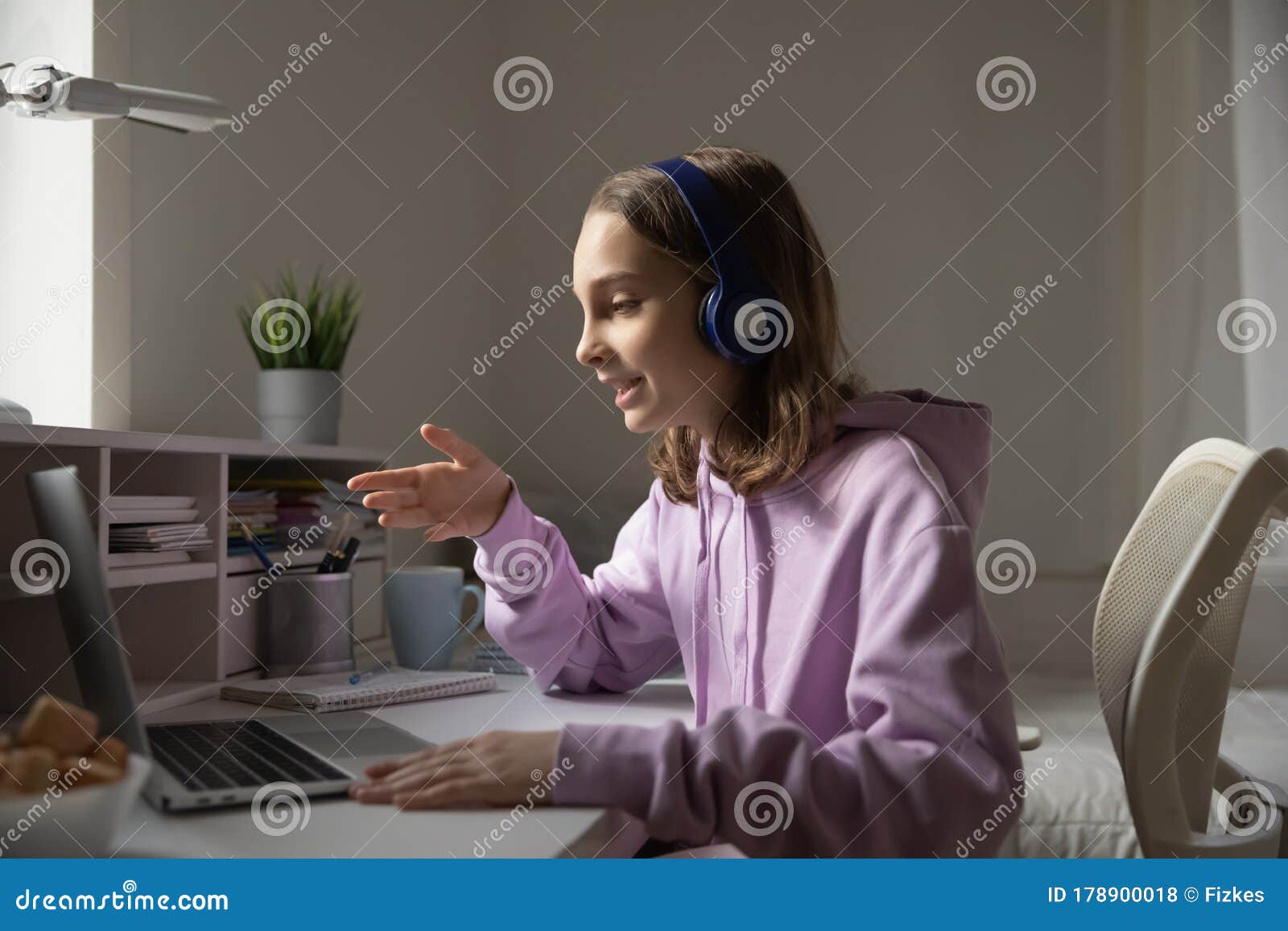 teen girl wears headphones conference calling studying with online tutor