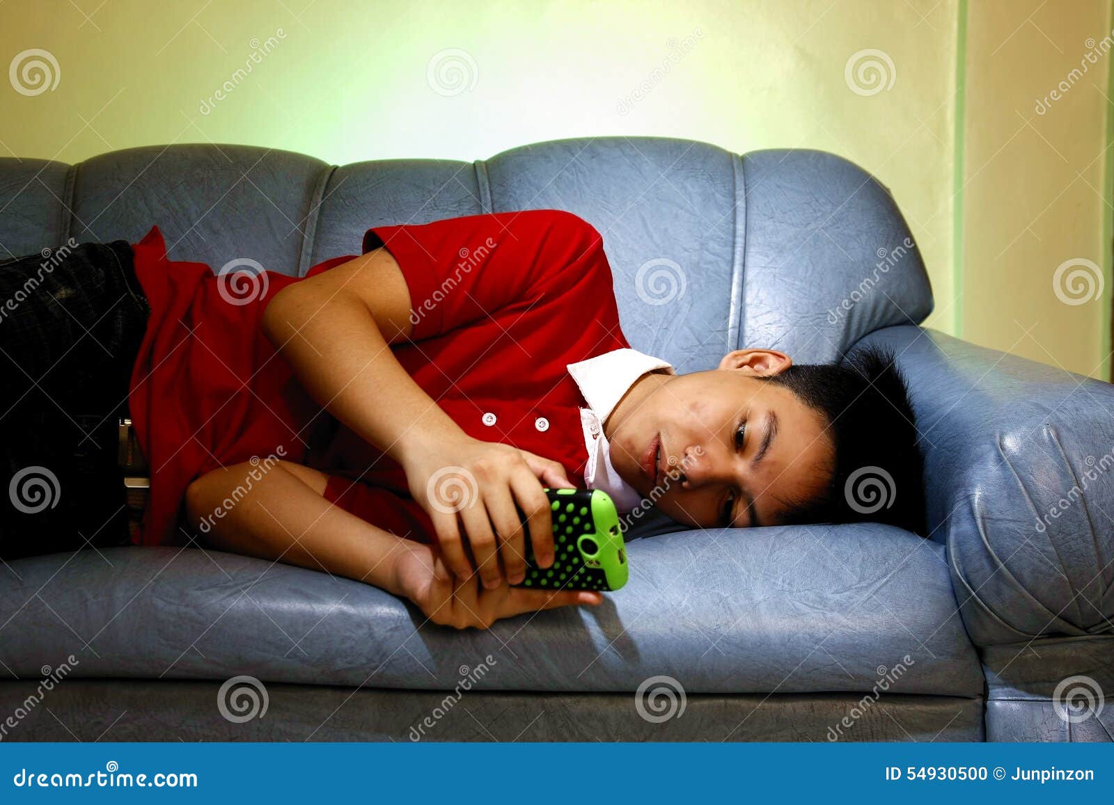 Teen using a smartphone while lying down on a couch and 