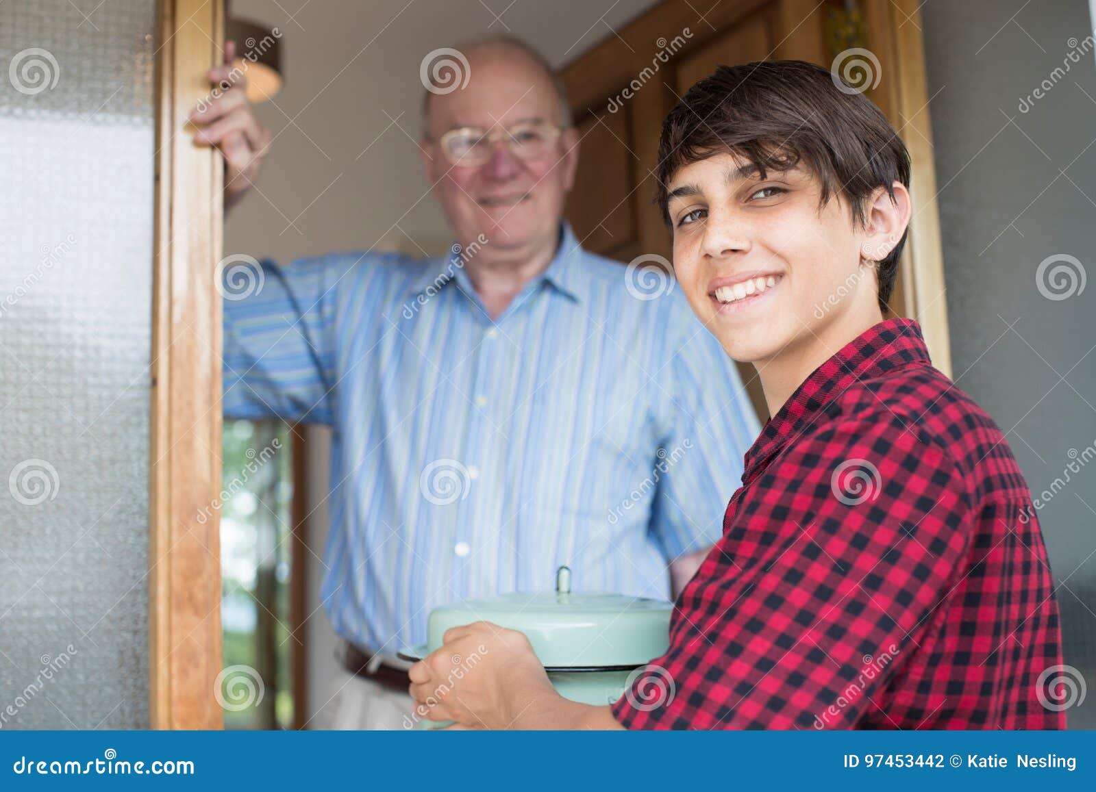 teenage boy bringing meal for elderly male neighbour