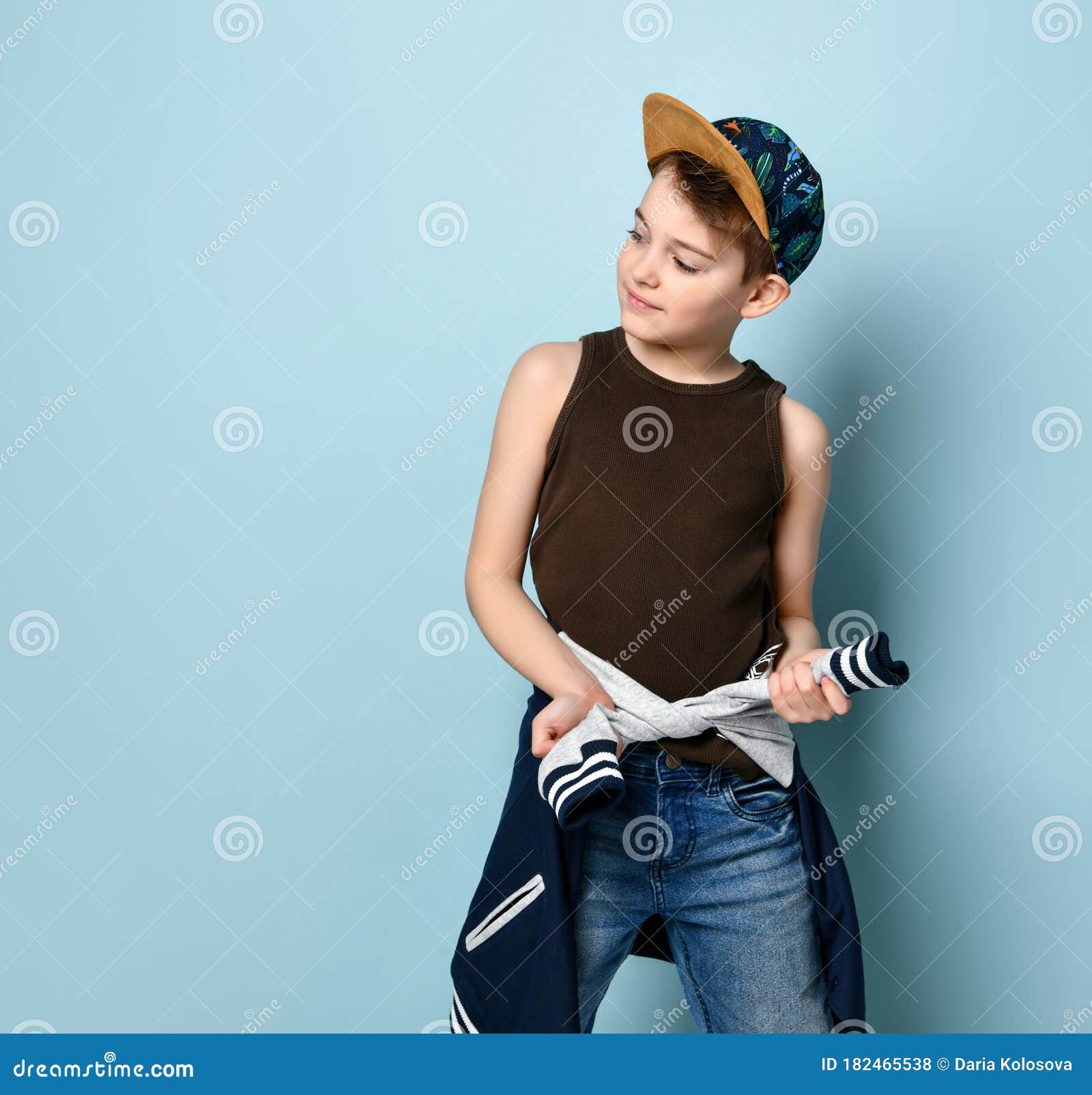 Teenage Boy in Cap, Brown Undershirt and Jeans. he is Tying Hoodie ...