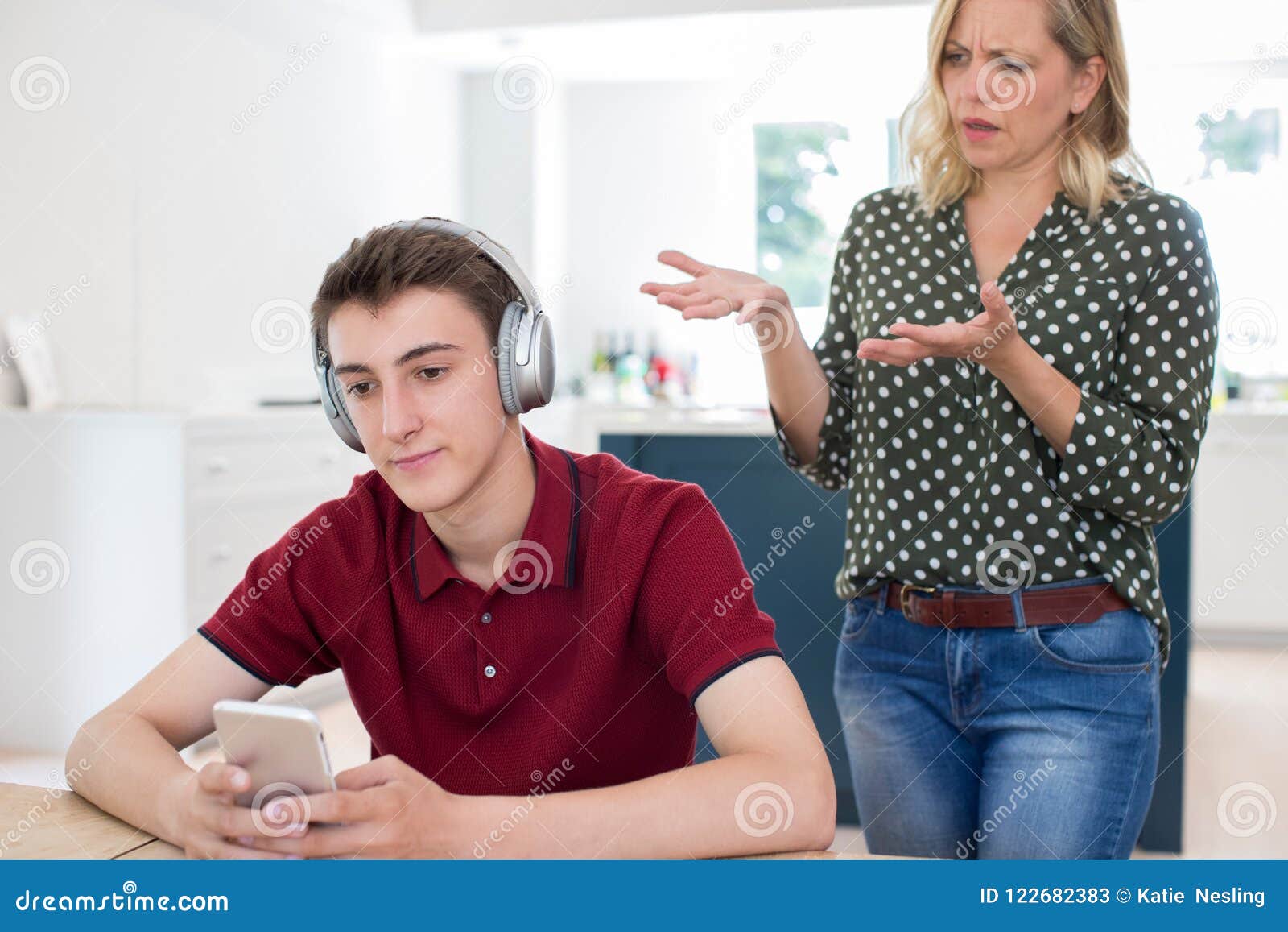 Teenage son listening music in headphones or playing online games ignoring  his mother Stock Photo - Alamy