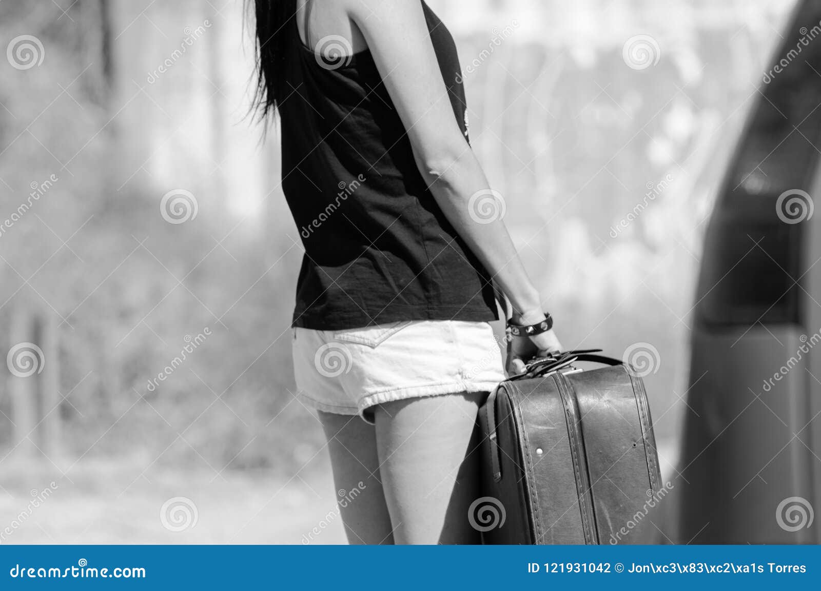 teenage brunette woman holding a large leather suitcase