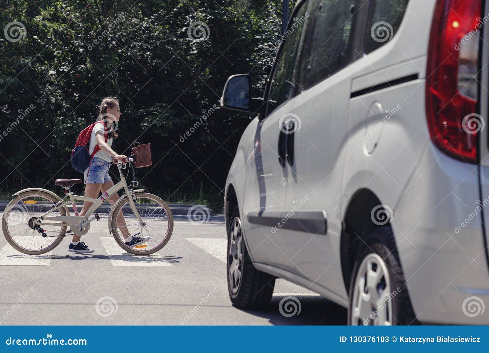 girl with backpack and bike on pedestrian crossing