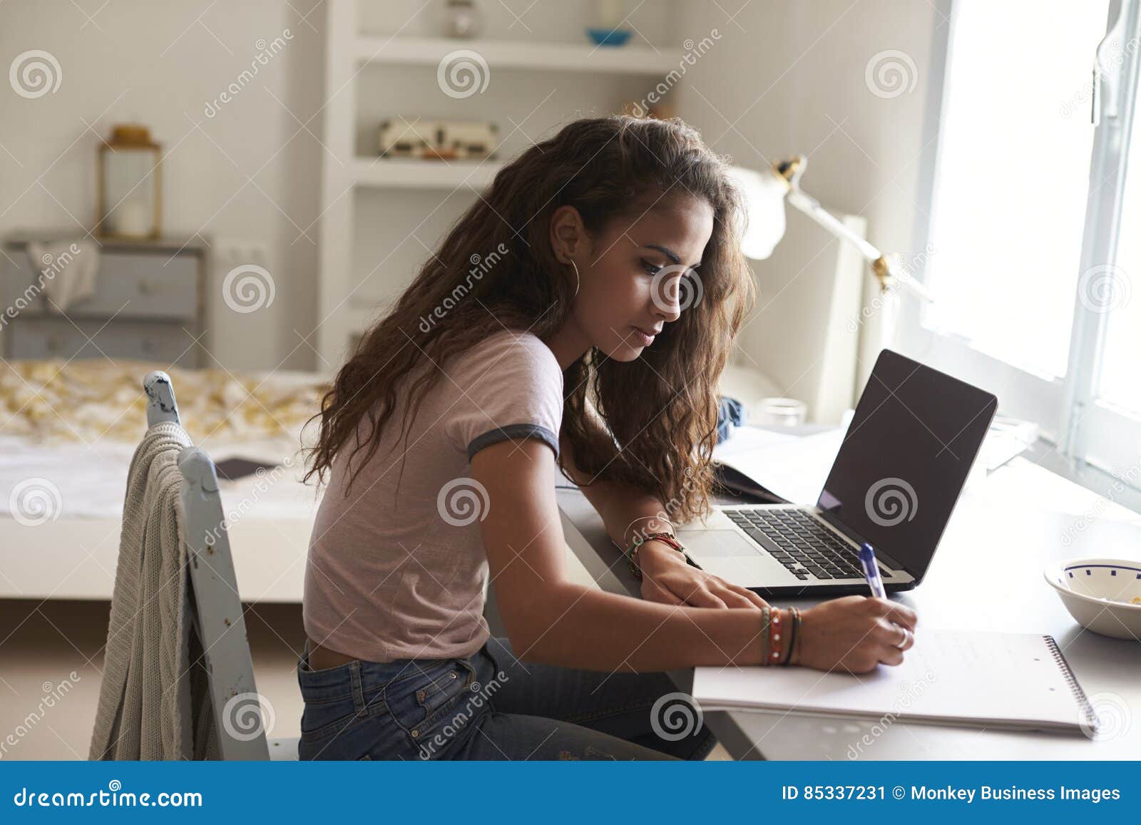 Teenage Girl Doing Homework At A Desk In Her Bedroom Stock Image