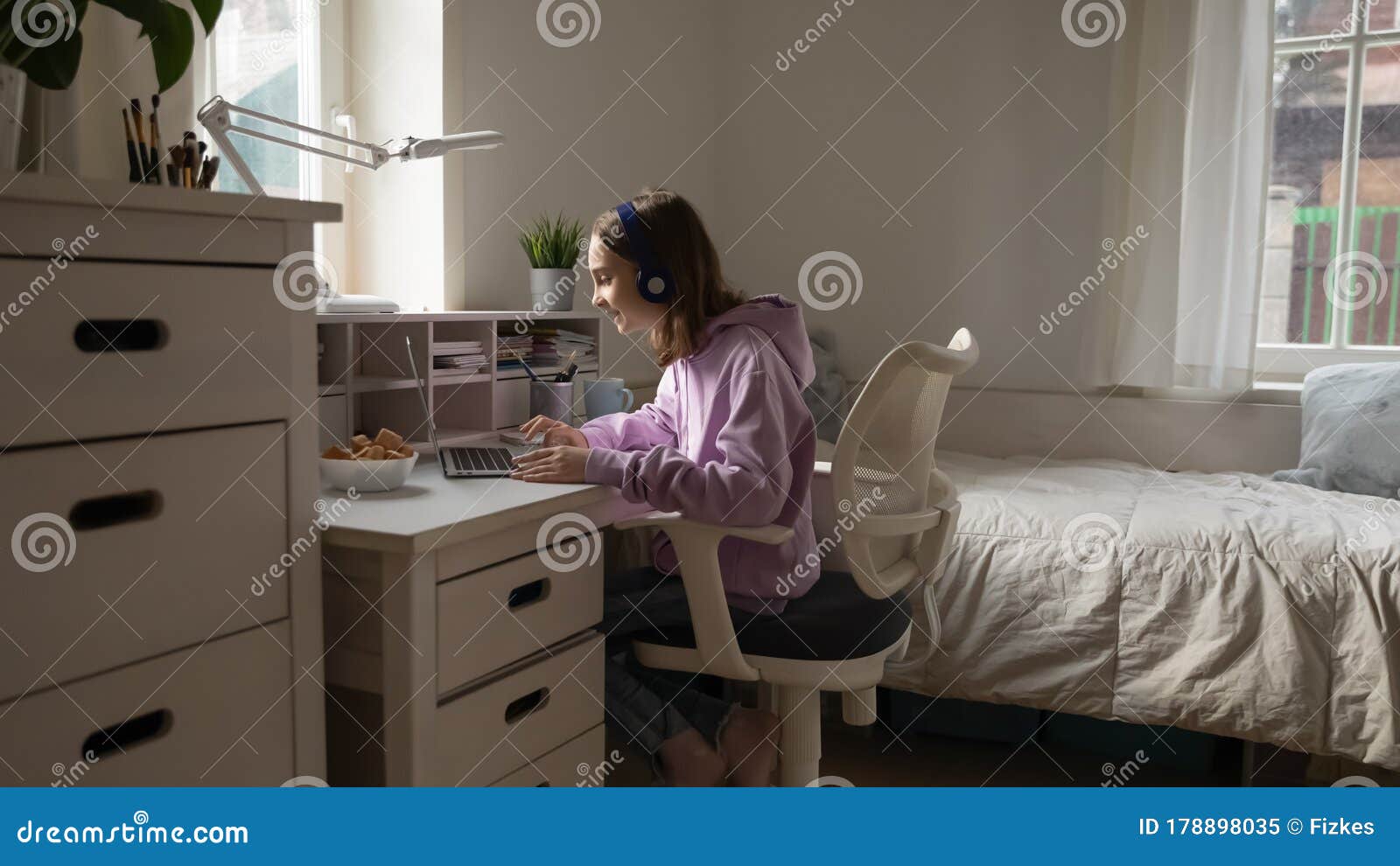 teenage girl wearing headphones elearning from home using computer app